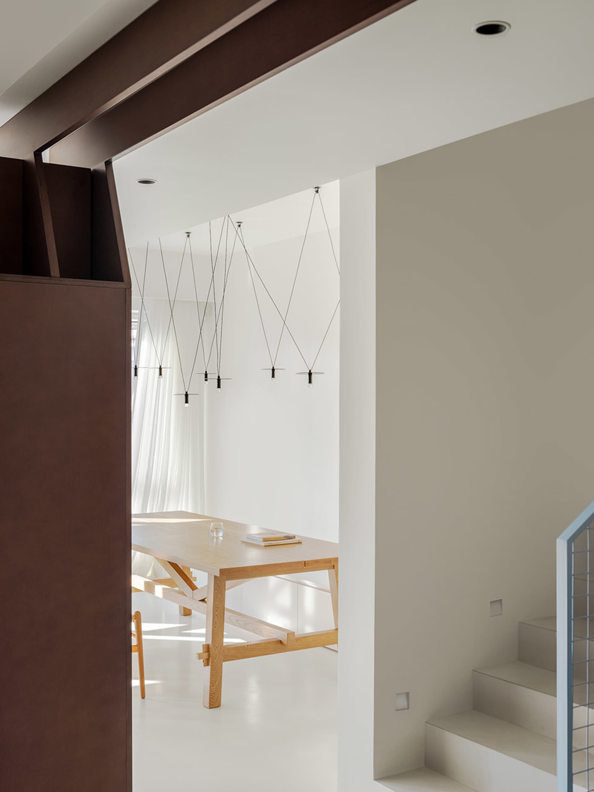 Open living space with a wooden dining table, chairs, and a modern couch, featuring clean lines and minimalistic decoration