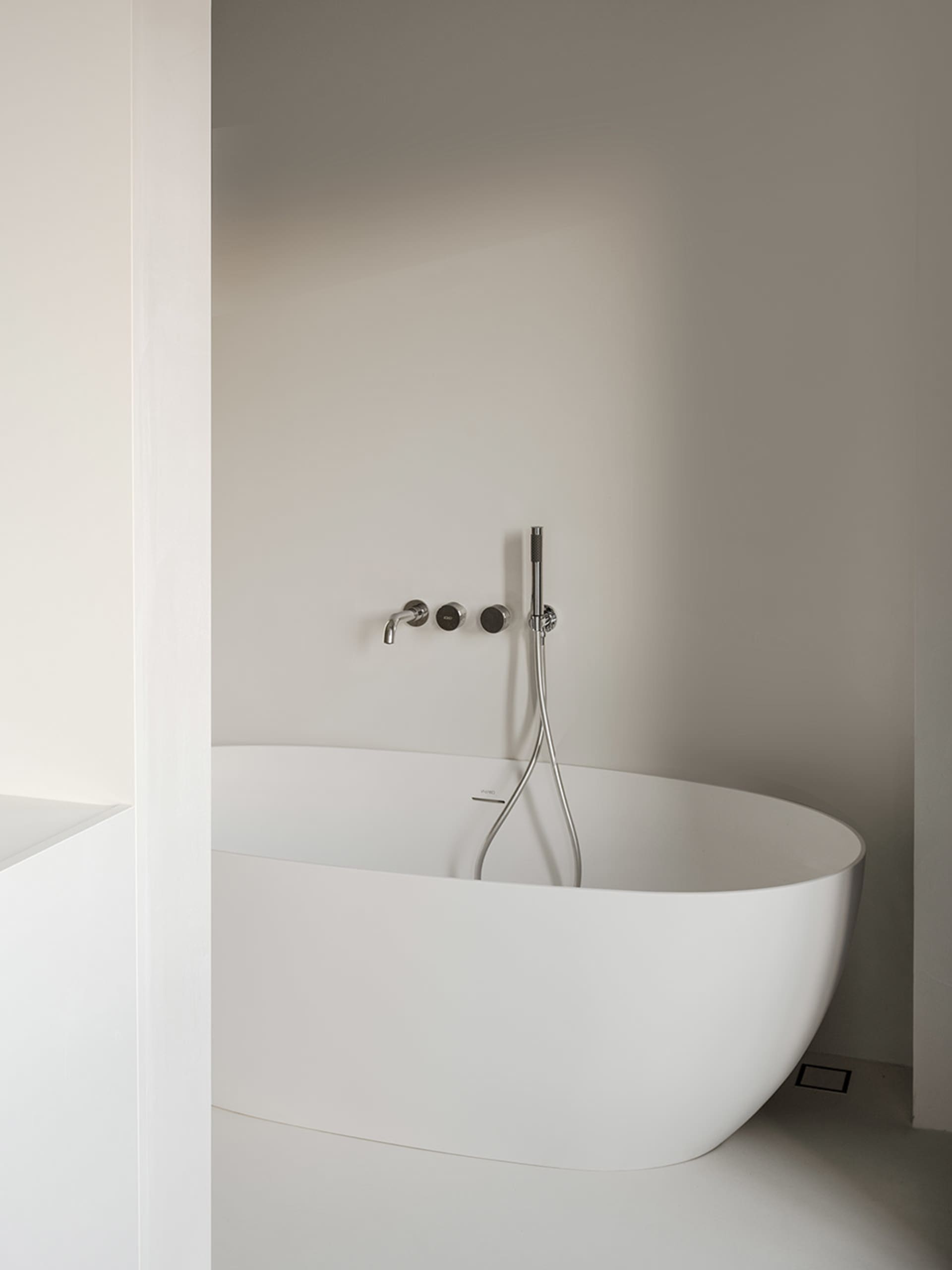 A modern bathroom with a round tub, white walls, and two faucets, giving a clean and bright appearance