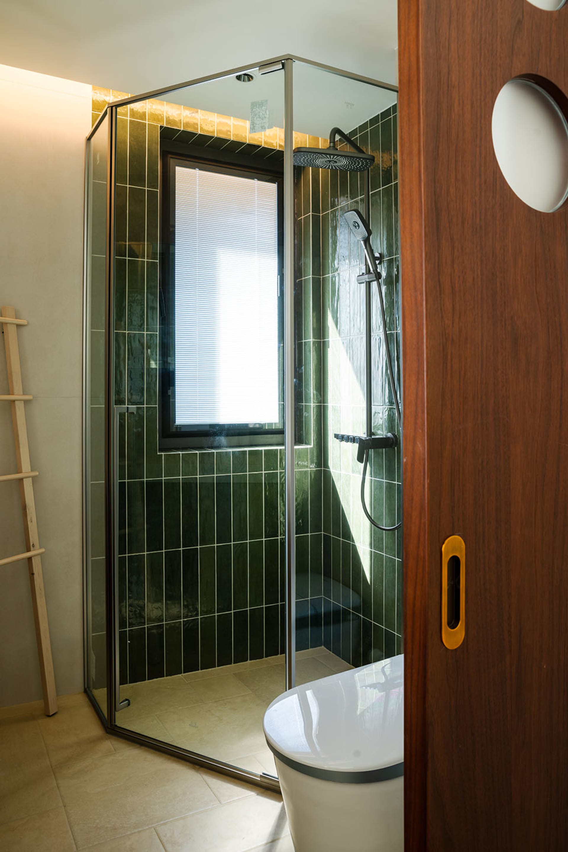 Bathroom with two showers, one with green tiles, and a sink on the right, creating a modern and sophisticated atmosphere