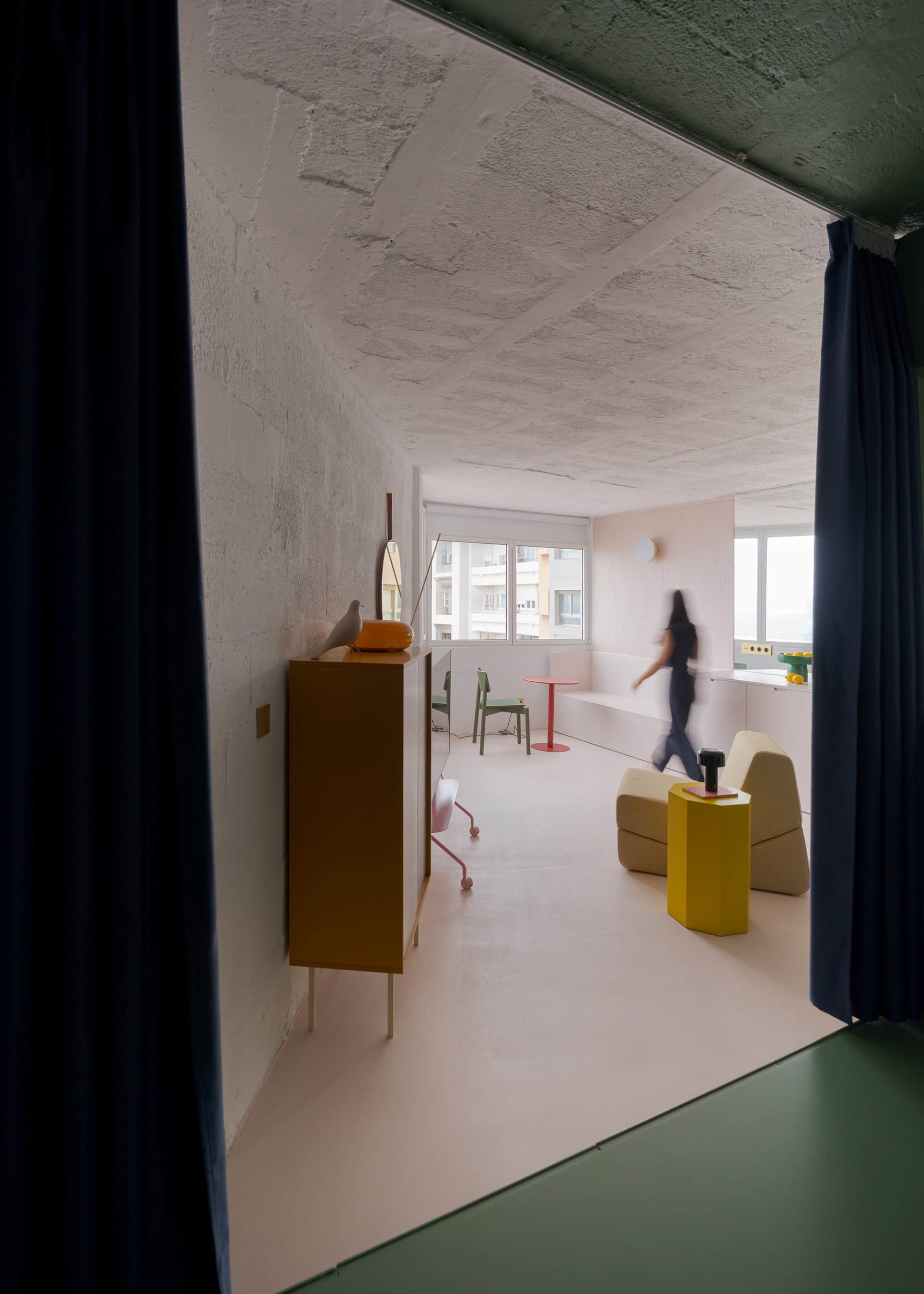 A modern dining space with a concrete wall, a dining table, chairs, and natural light