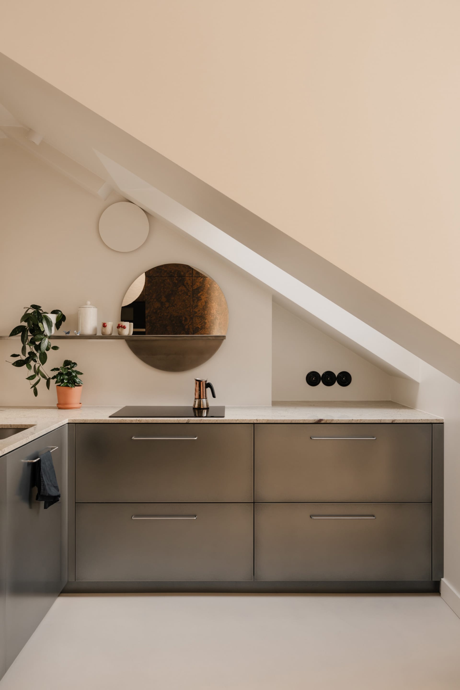 A cozy kitchen with a sink, countertop, and various decorative items such as potted plants, bottles, cups, and vases