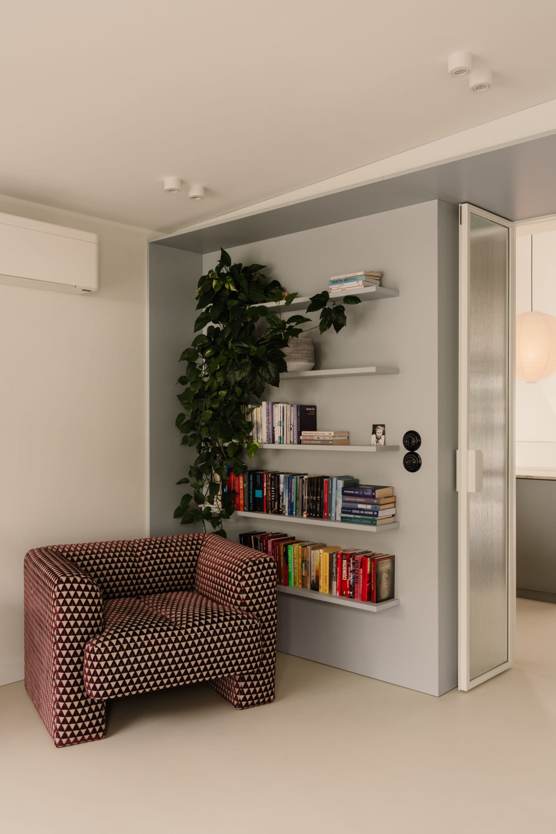A cozy reading nook with a chair, bookshelves, and a doorway, featuring a warm and inviting atmosphere with books and comfortable seating