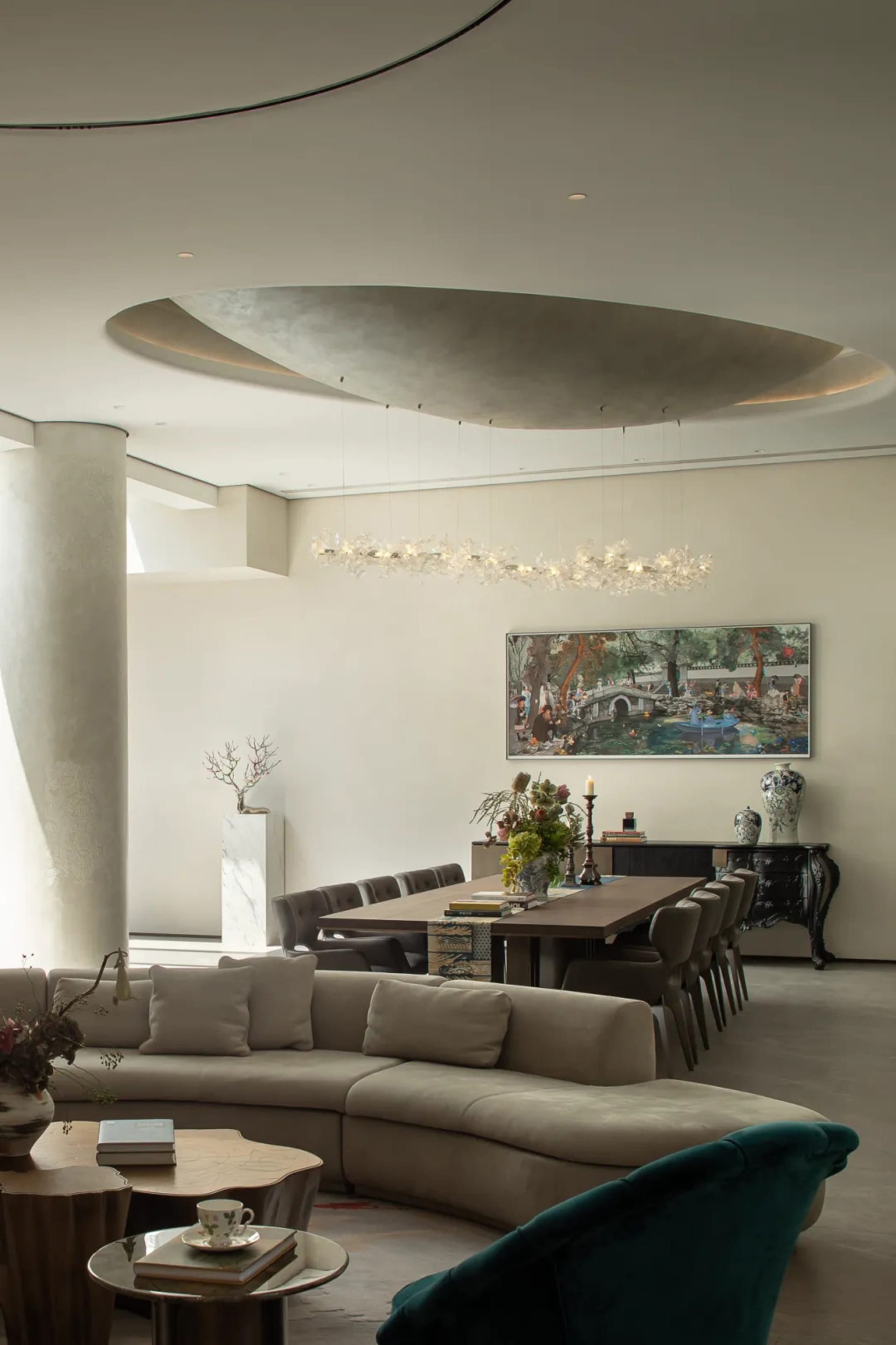 A modern living room with a large couch, dining table, chairs, potted plant, and vases, set against a neutral background