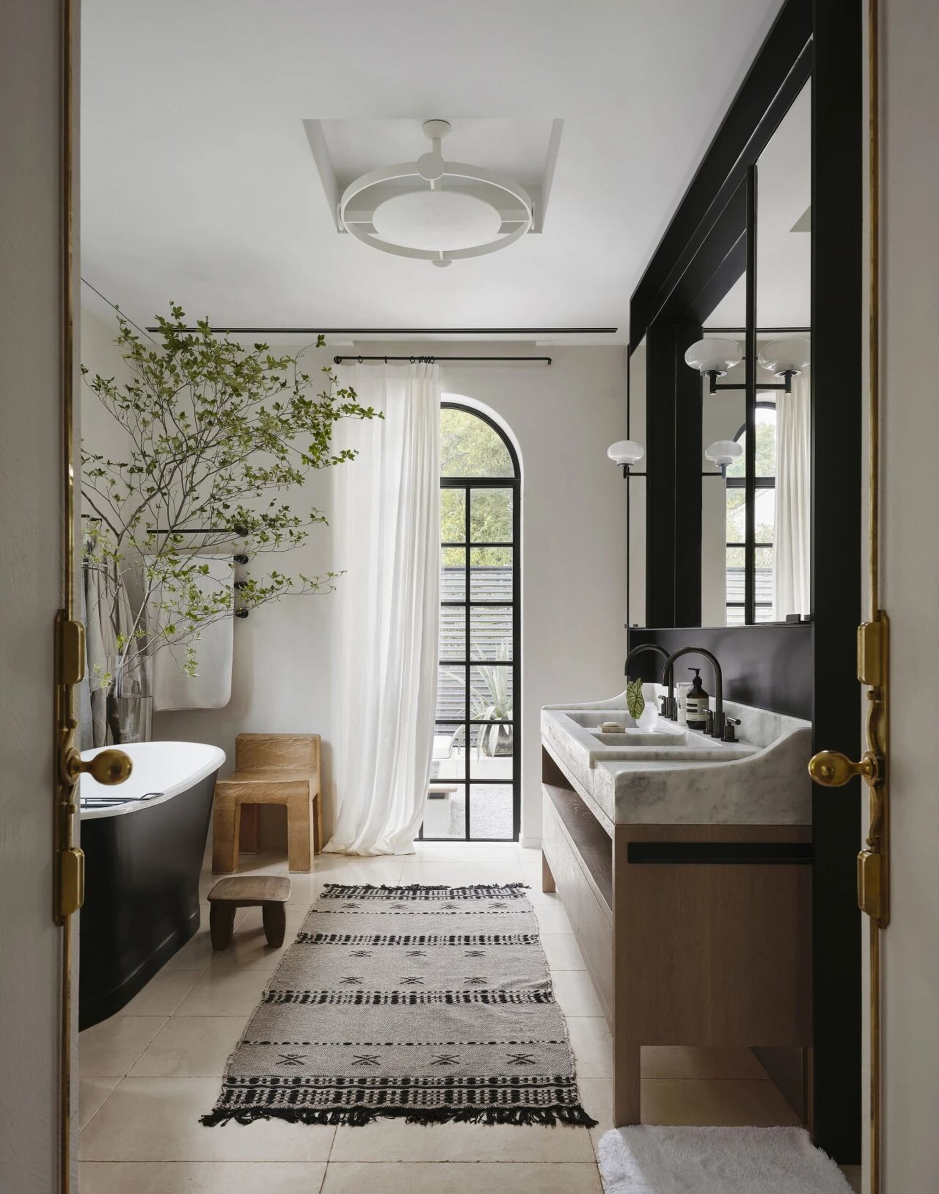 Luxurious bathroom with a white bathtub, two sinks, and a large window for natural light