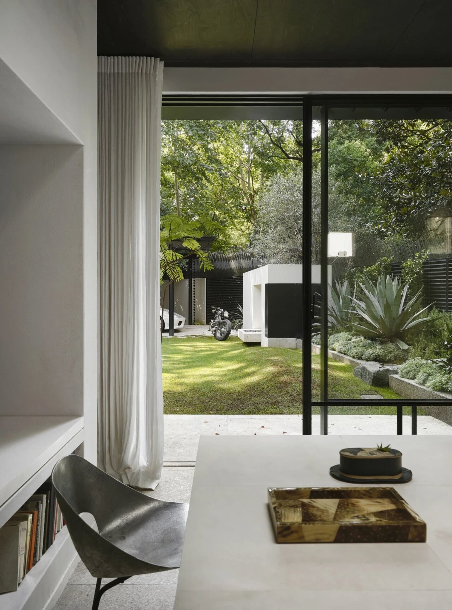Modern living room with a dining table and chairs, black and white elements, and a motorcycle parked in front of the table
