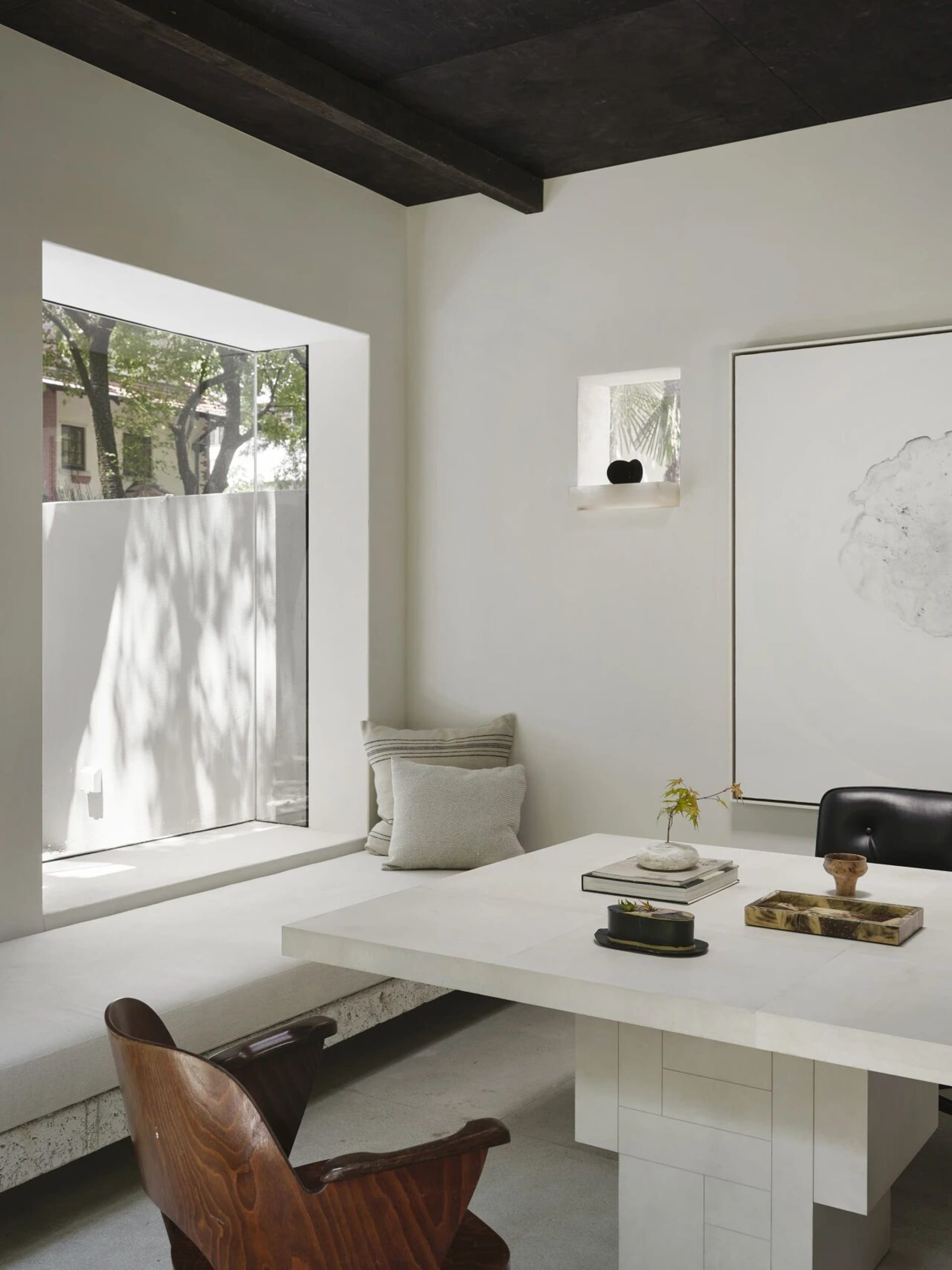 Open living area with a white table, chairs, couch, and a potted plant, surrounded by natural light and bright atmosphere