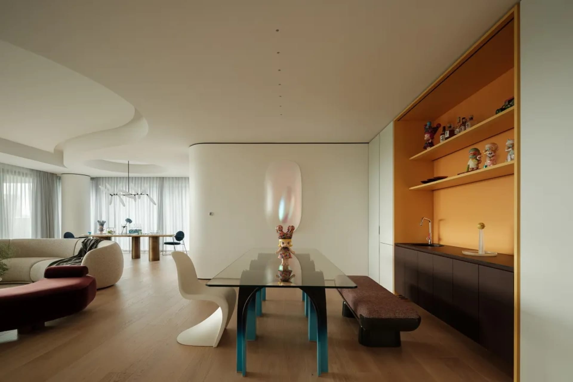 Open modern living space with a dining table, chairs, a couch, and a vase, well-lit and inviting