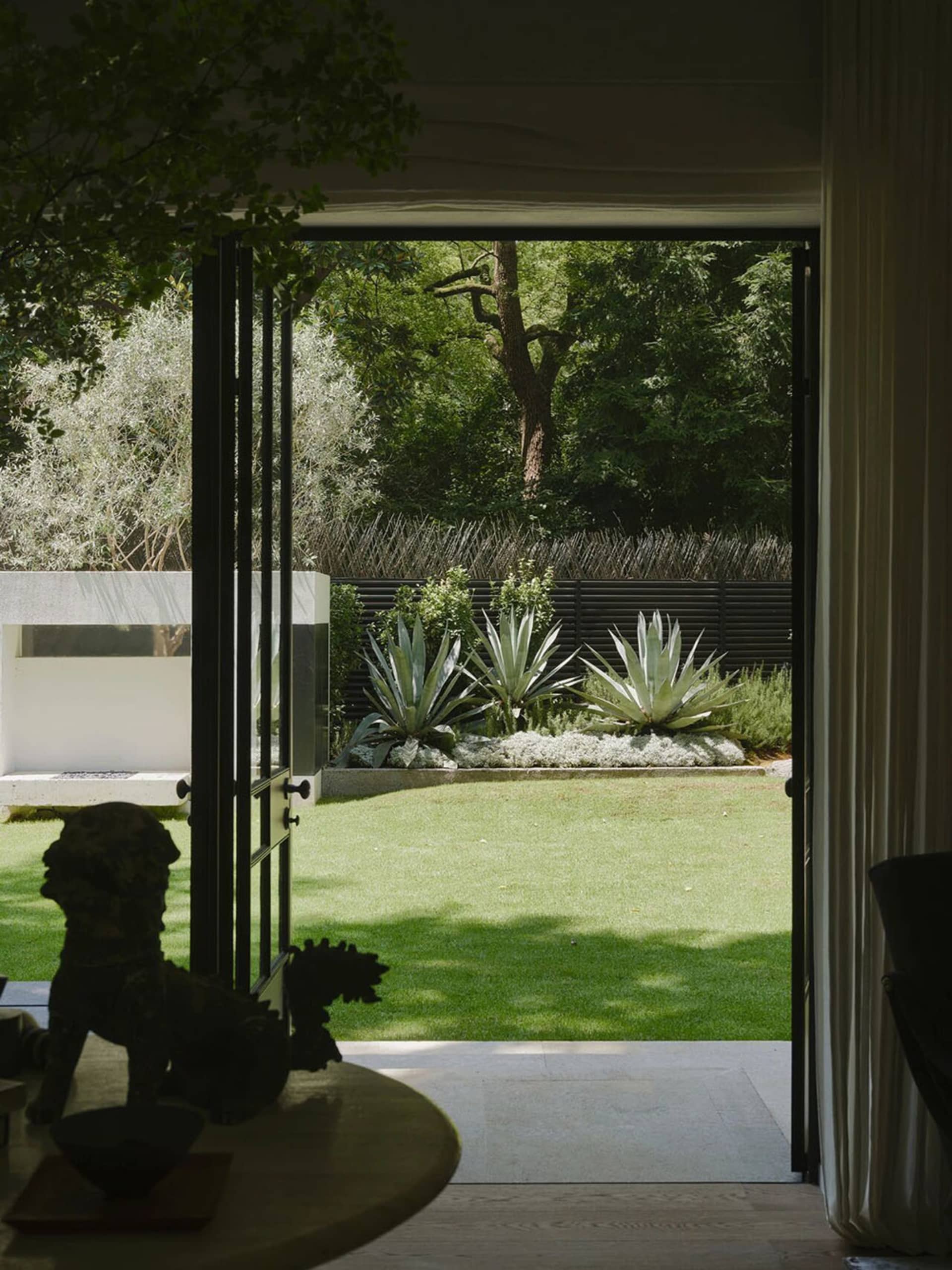 A well-maintained outdoor living area with a green lawn, potted plants, and a patio