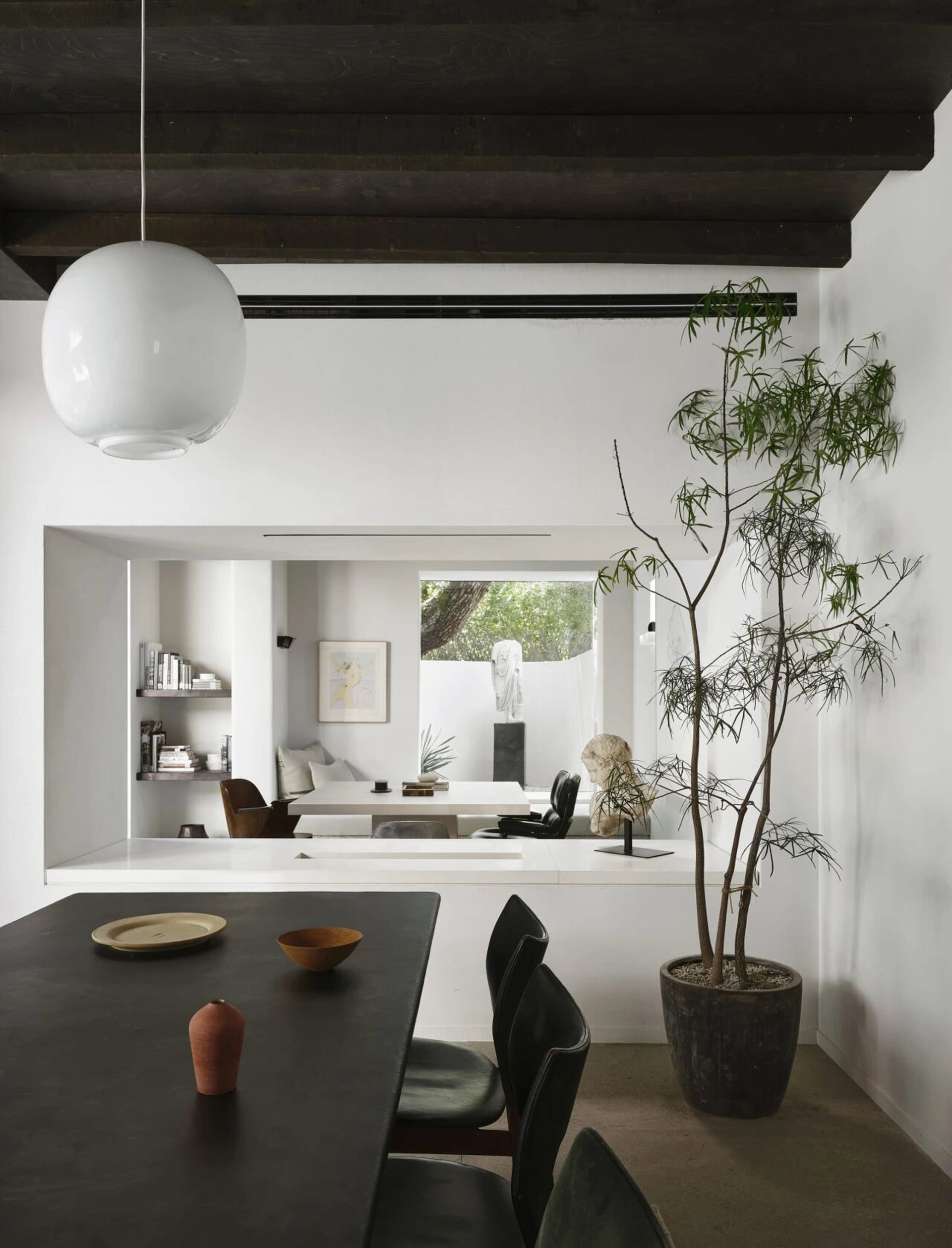 Open living area with a dining table, chairs, a potted plant, and a vase, surrounded by ample seating options and bright atmosphere