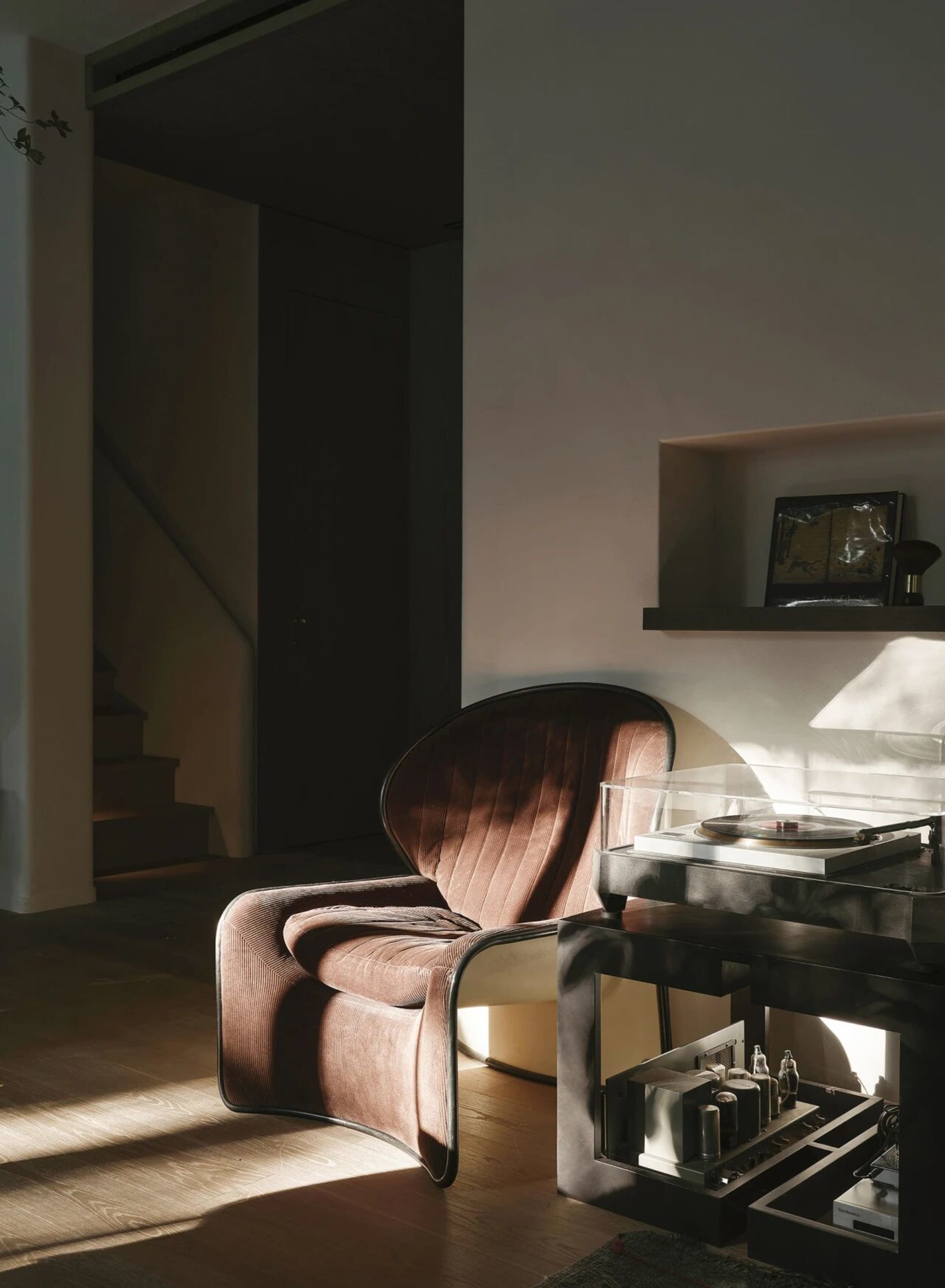 A modern living area with a brown leather chair in front of a white wall, accompanied by decorative bottles, conveying a sense of comfort and sophistication