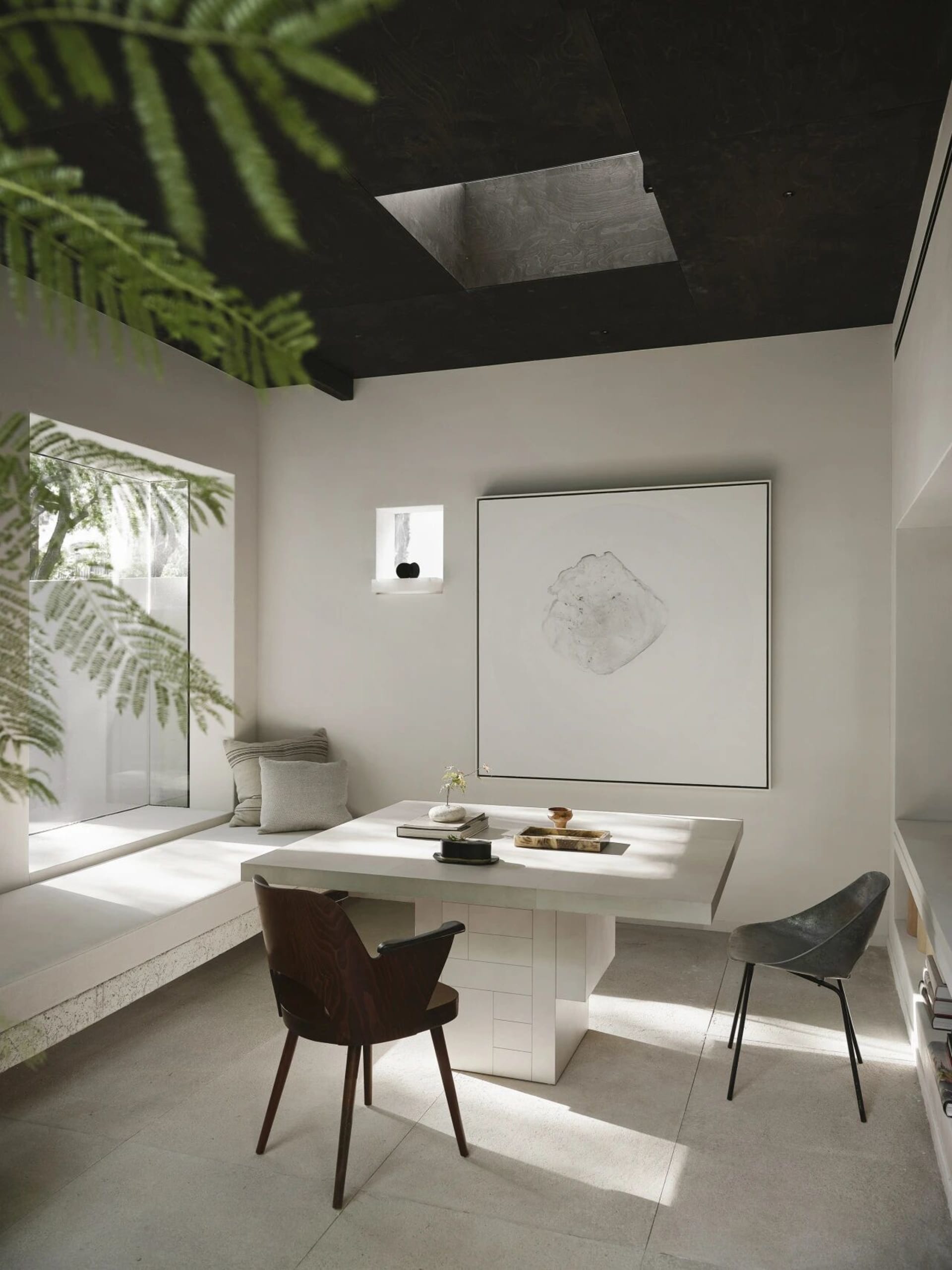 A well-lit living area with a white table surrounded by chairs, creating a cozy seating arrangement, with natural sunlight coming through windows