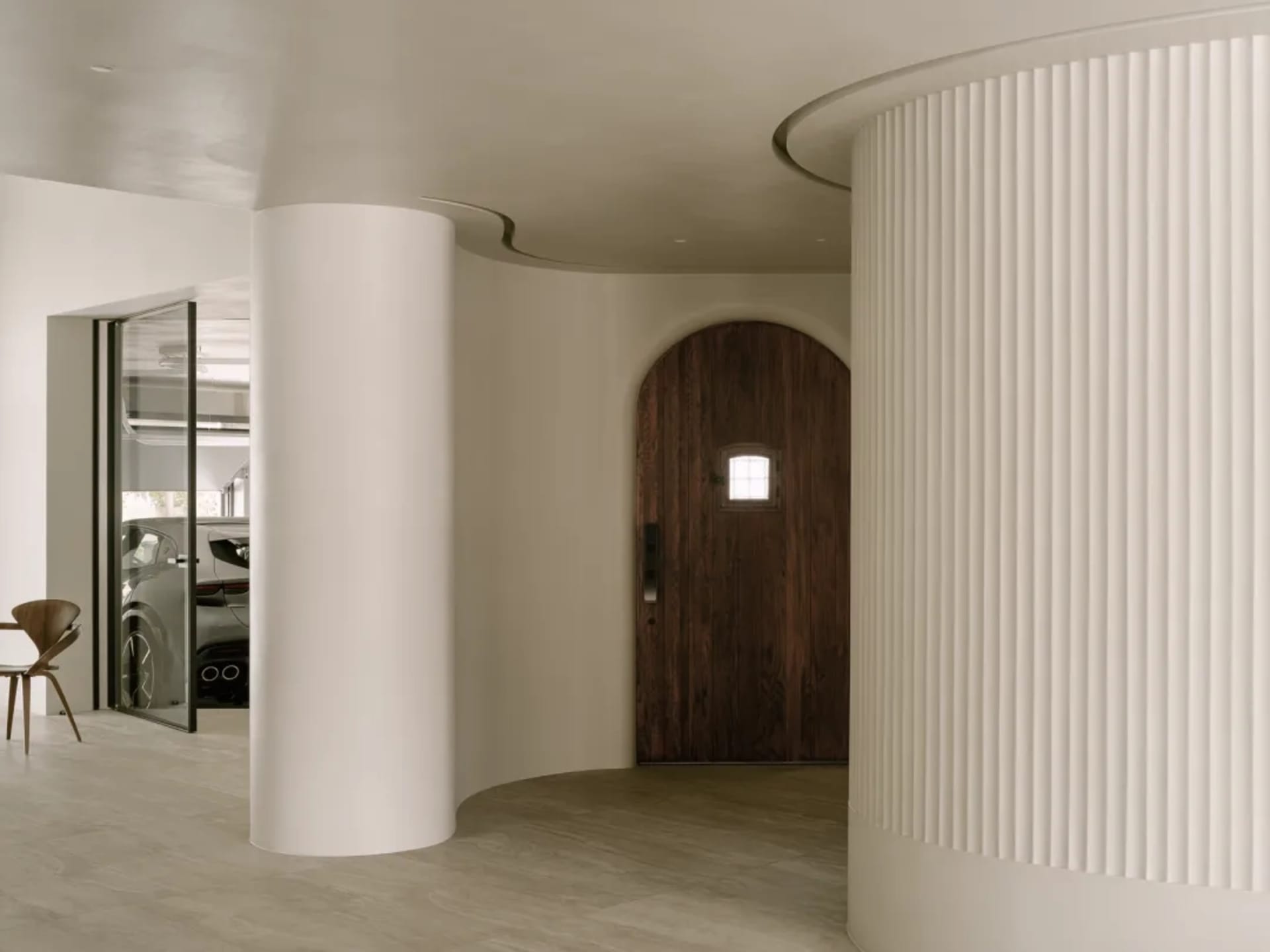 A curved hallway with two doors, one near the center and another towards the right, featuring wooden walls and a cozy atmosphere