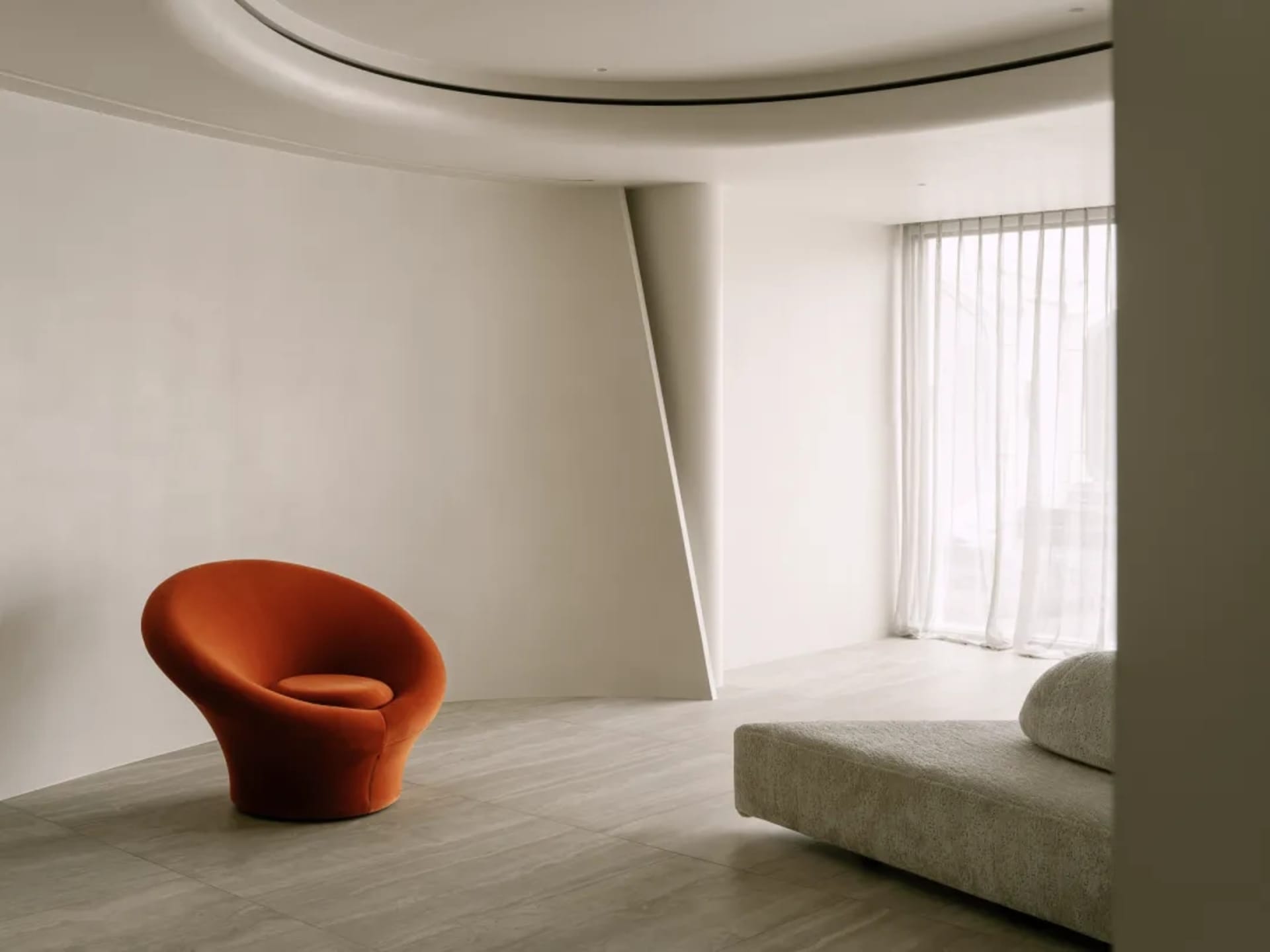 Modern living room with a minimalist aesthetic, featuring a large couch, two chairs, and a dining table, with a focus on functionality and openness