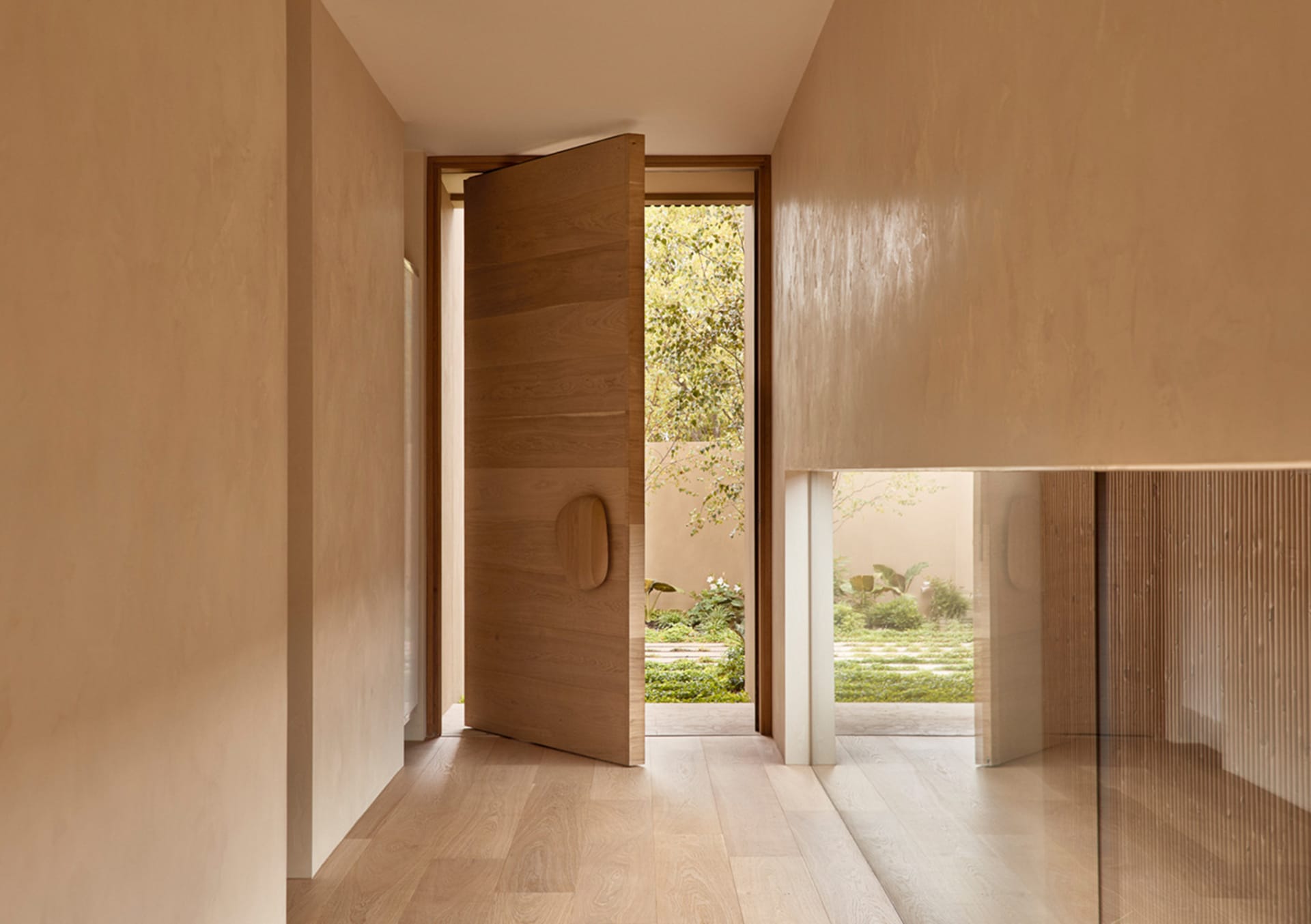 A warm and inviting house entrance with a wooden doorway and a large window allowing natural light to enter the space