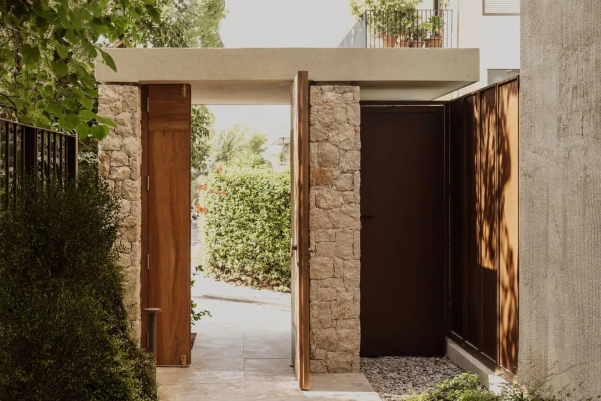 A house entrance with a stone doorway, wooden frame, and potted plants, creating a cozy and inviting living space