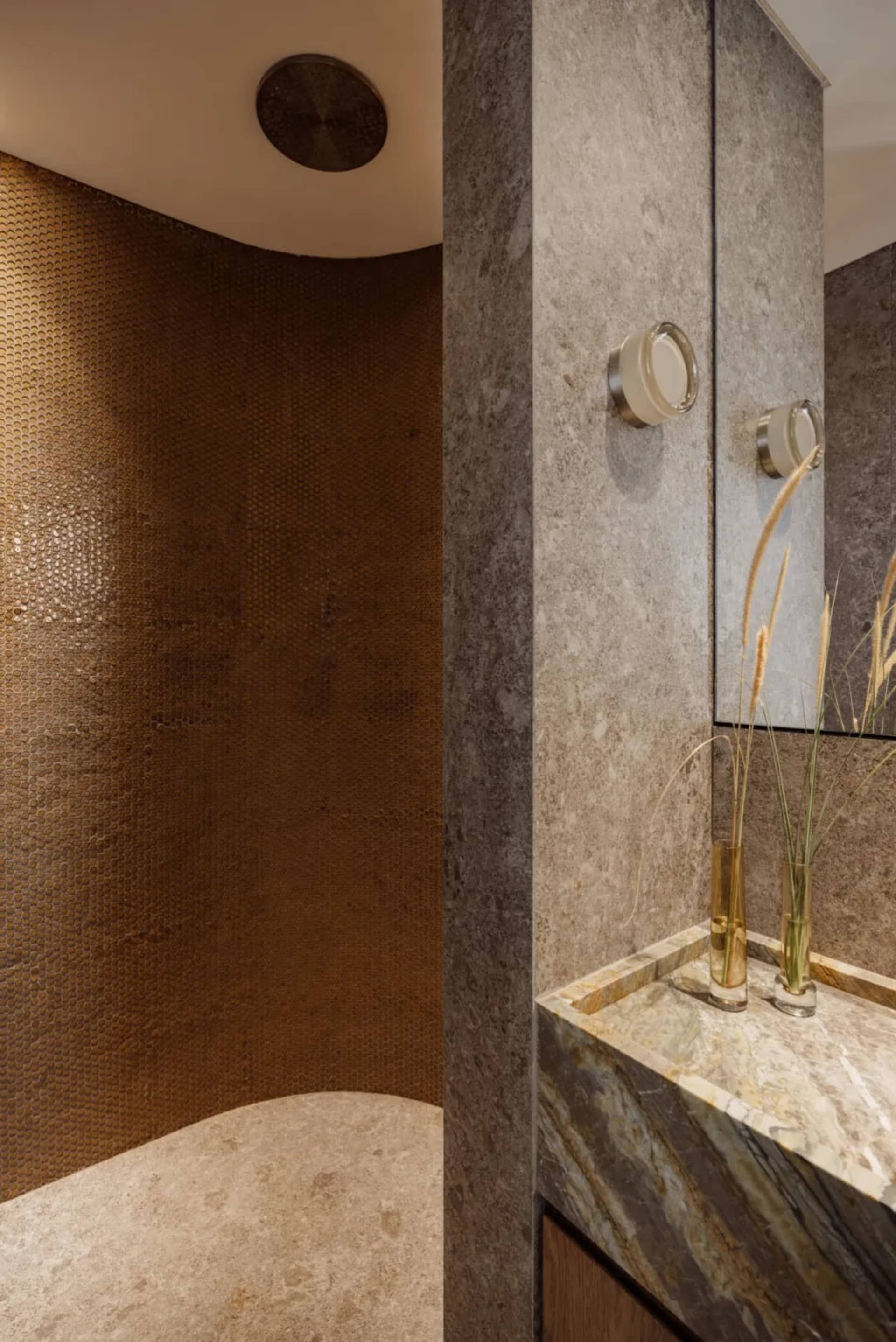 Bathroom with two sinks, a mirror, and brown tile walls creating a warm atmosphere