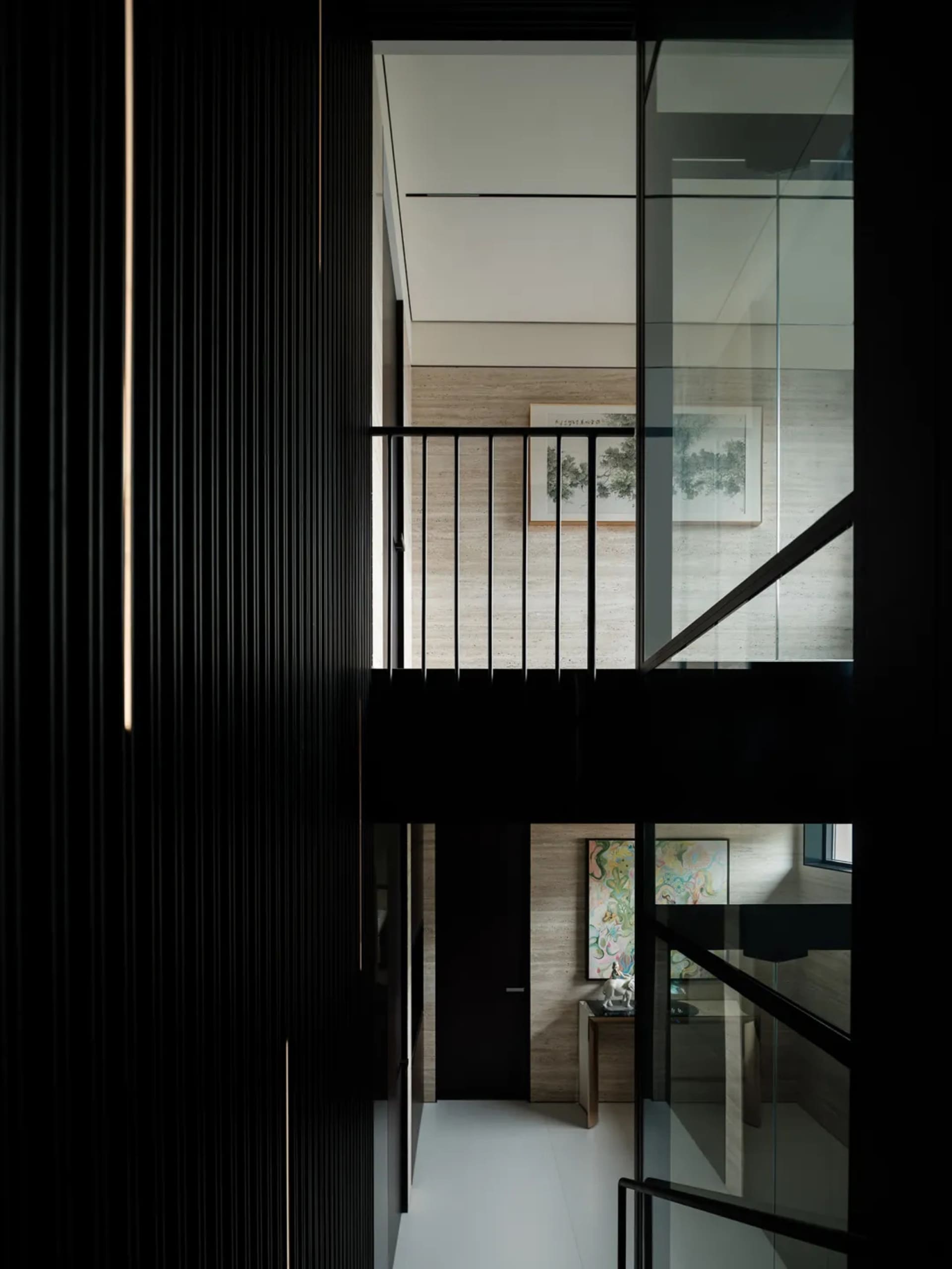 A dark and mysterious interior staircase with wooden steps and a black railing, featuring a painting on the wall above