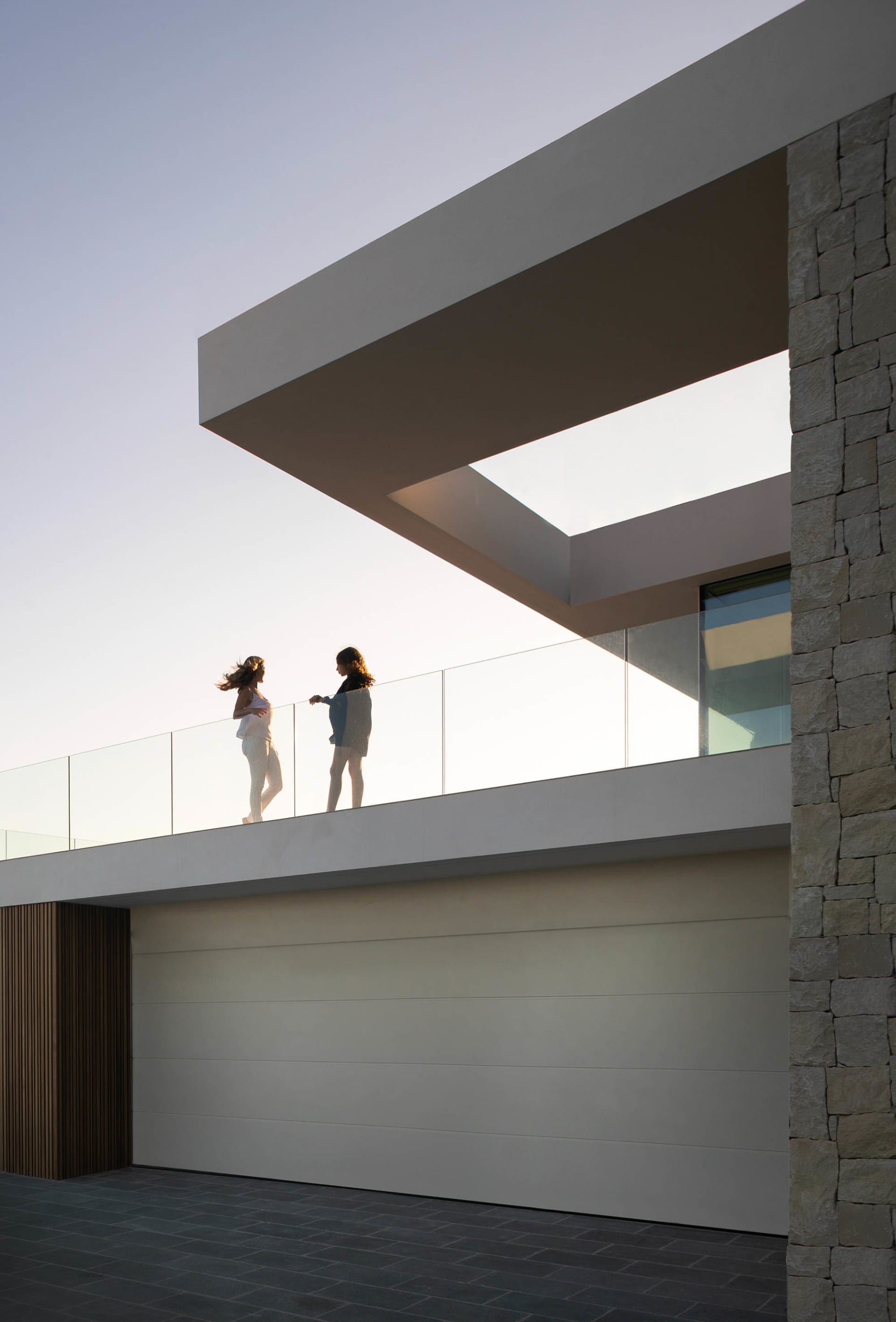 Two women standing on a balcony overlooking an urban landscape with buildings in the background