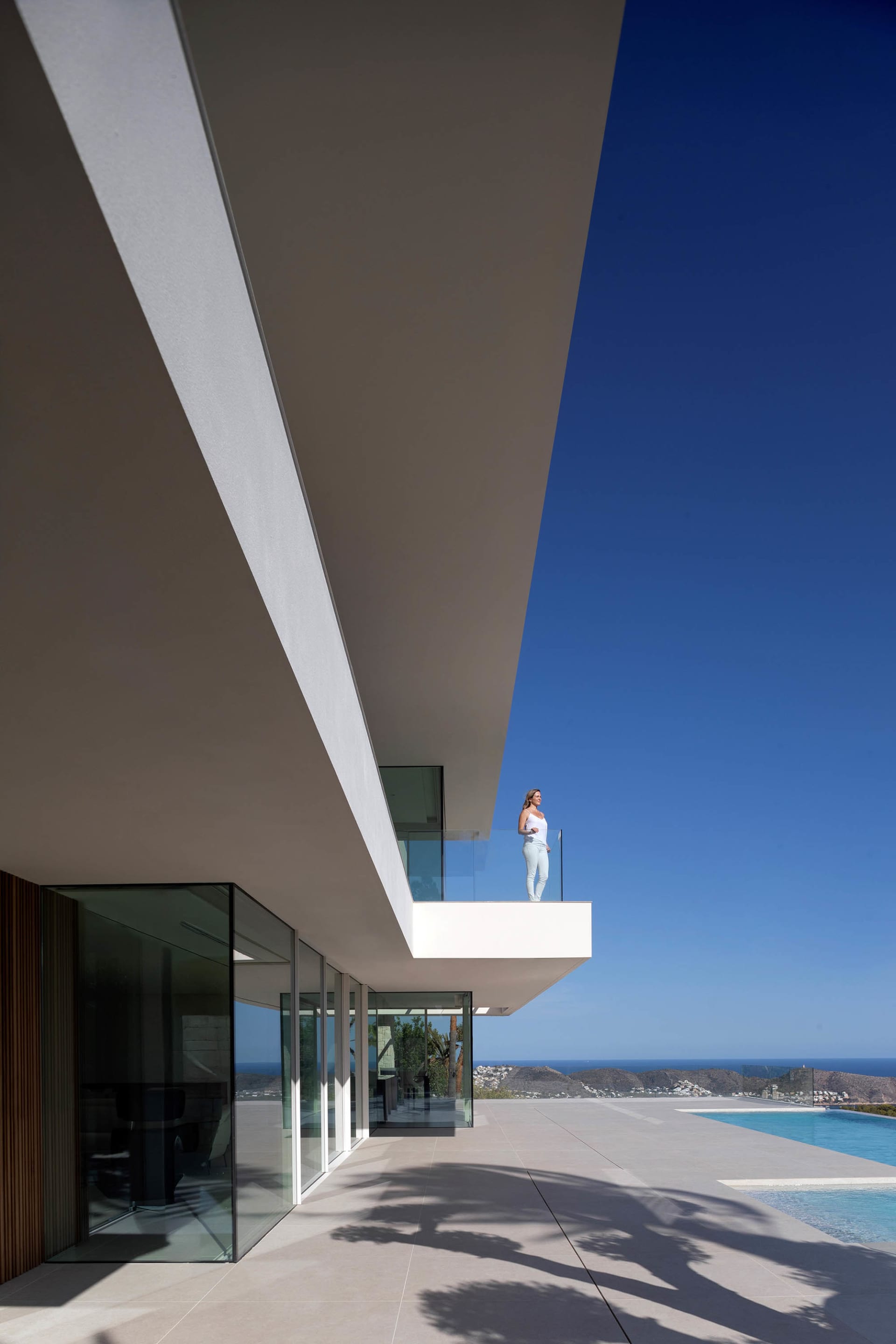 A modern house with a glass wall overlooking the ocean, featuring a serene and relaxing atmosphere with clean lines and minimalistic elements