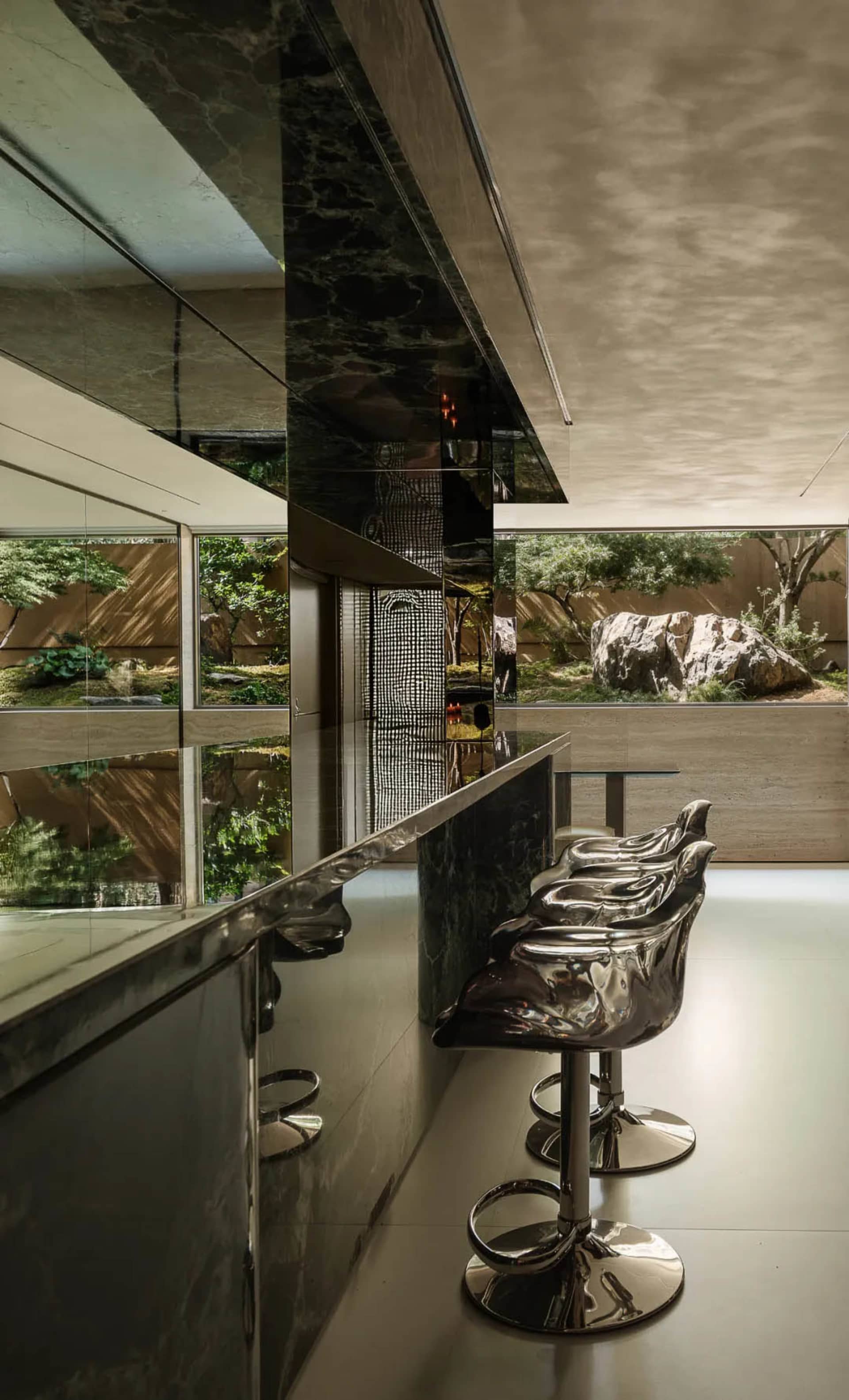 A modern bar area with a sleek counter, two sinks, and comfortable chairs for socializing and enjoying drinks