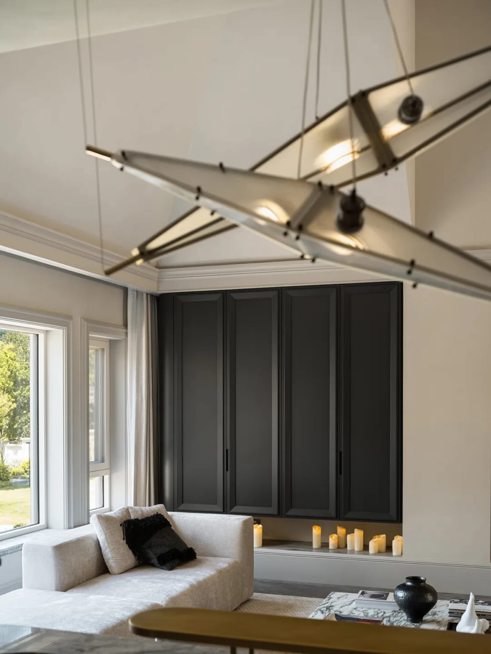 Cozy modern living area with a black cabinet, a couch, a chair, and candles, featuring a predominantly white color scheme and natural light