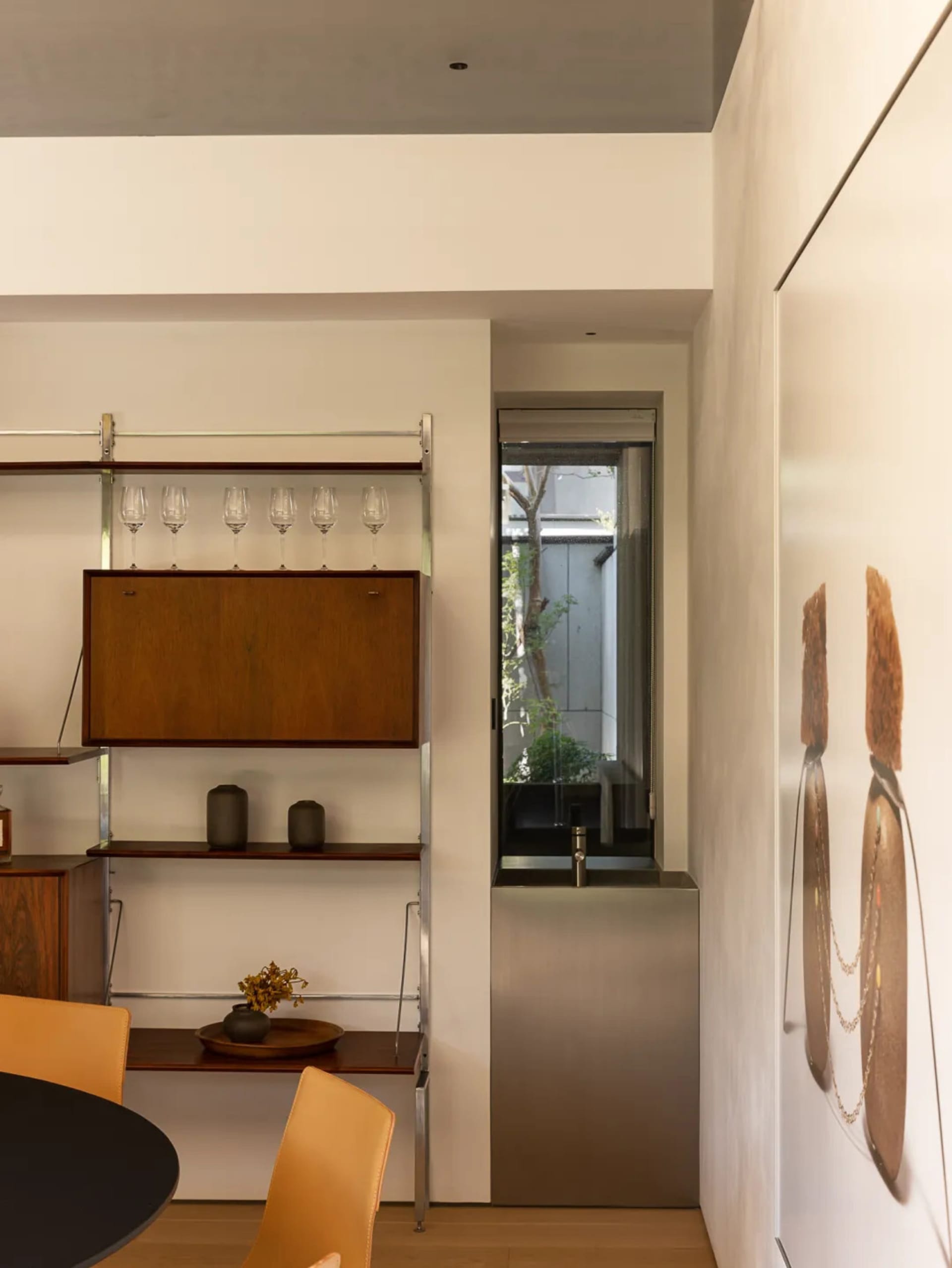 Modern kitchen dining space with a sink, dining table, chairs, and wine rack, featuring white walls and a well-organized atmosphere