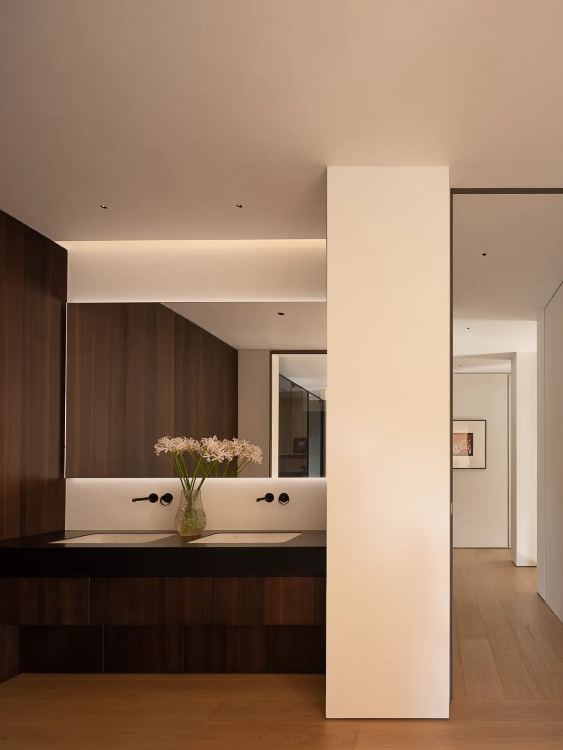 Modern bathroom with two sinks, wooden accents, and elegant vases, creating a warm and inviting atmosphere