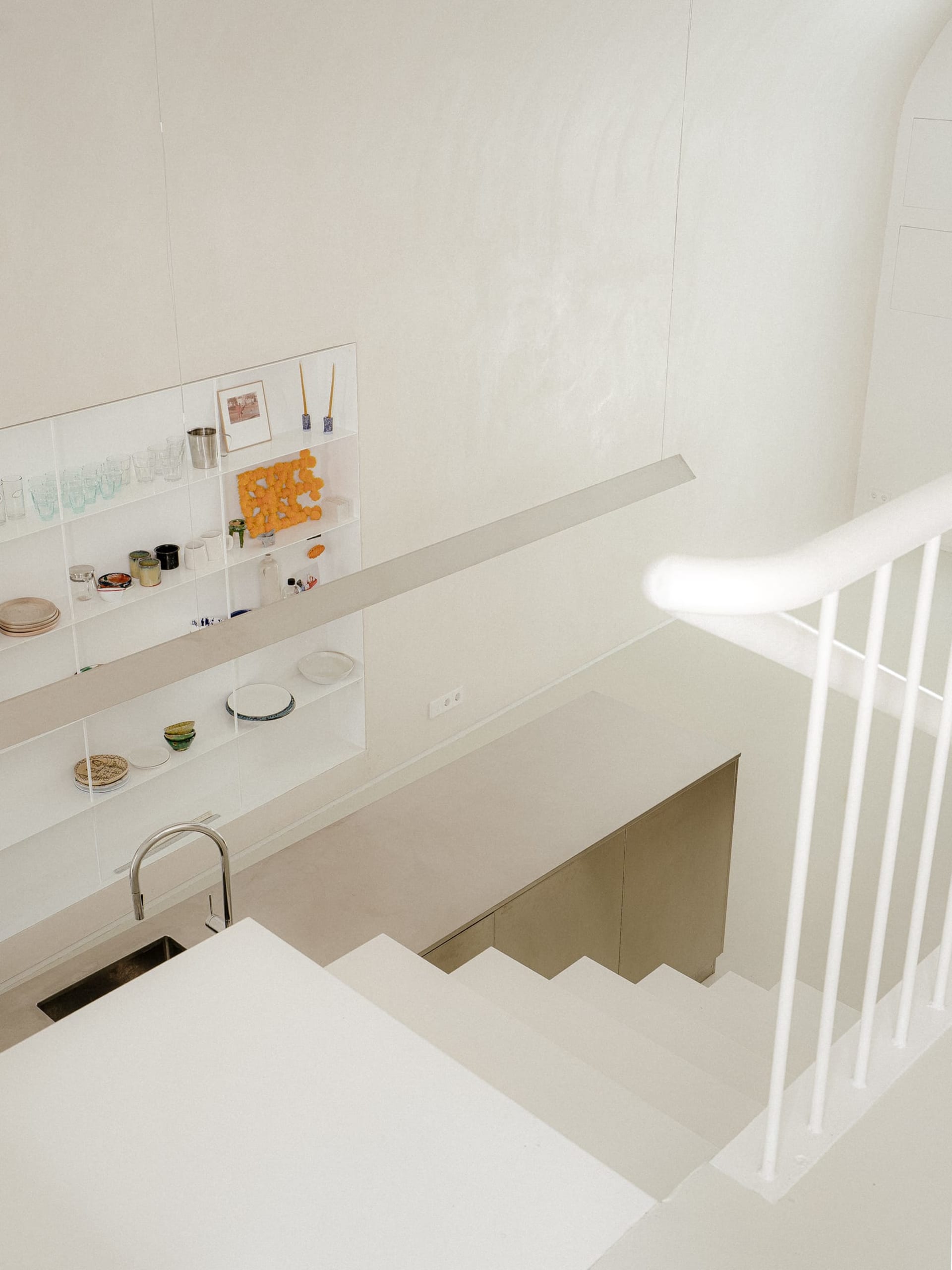 A well-organized kitchen with white walls and floors, featuring various objects and a sink, creating a functional living space