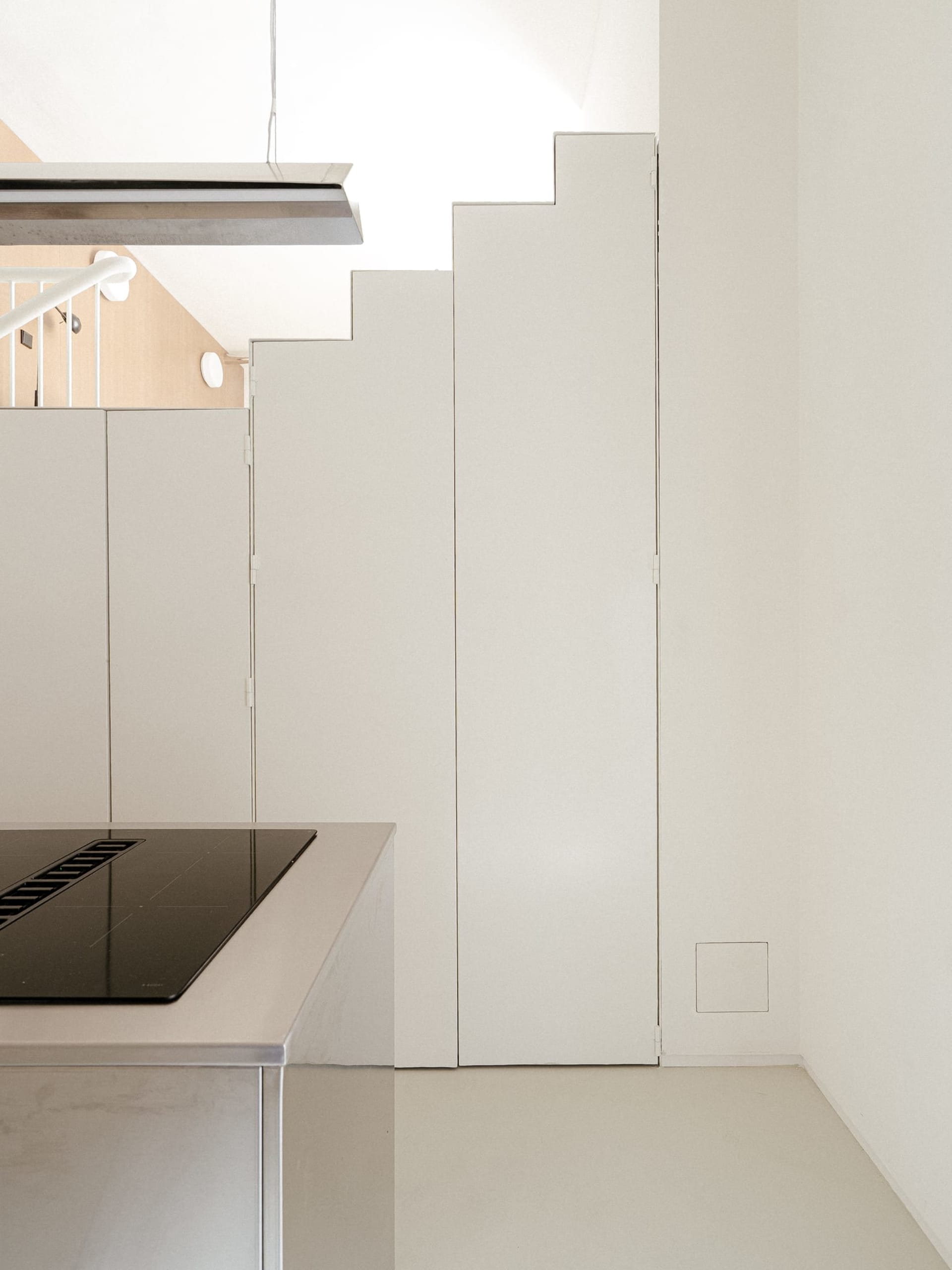 Modern kitchen with white walls and cabinets, featuring a stove top oven, refrigerator, and two sinks, with a focus on functionality and clean lines