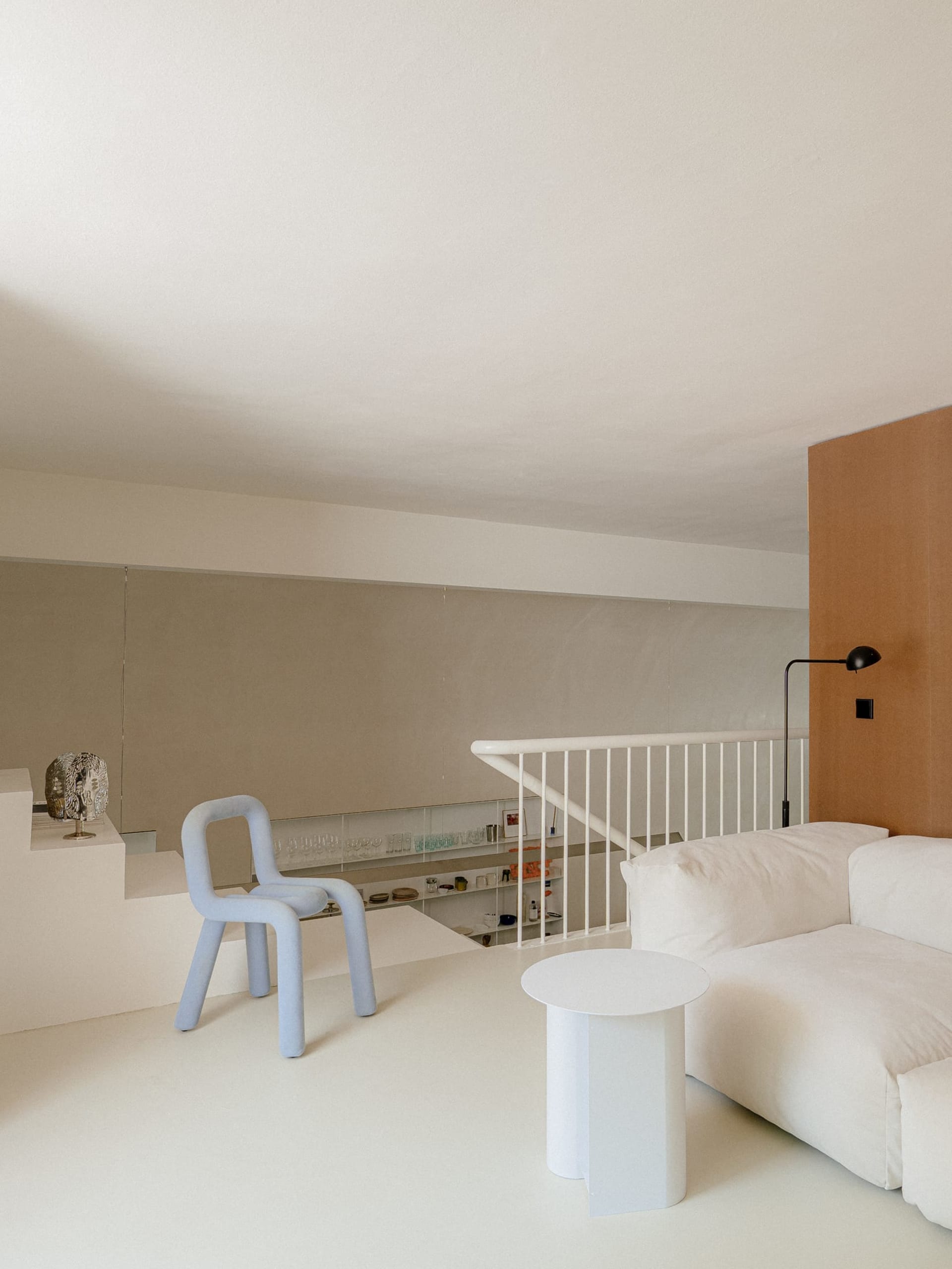 Open living area with a white couch, two chairs, a dining table, and scattered bottles, set against a clean and minimalist background