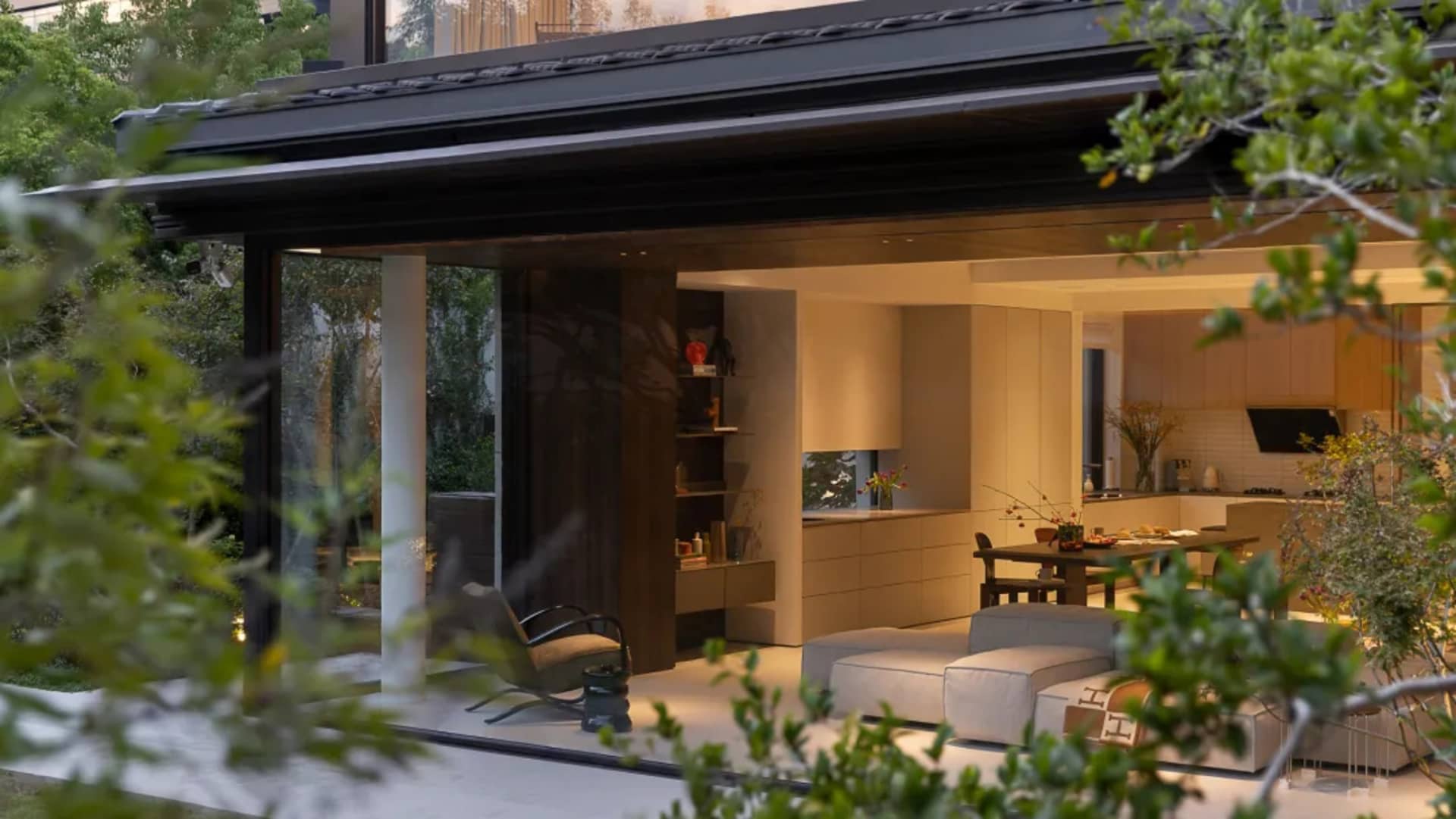 Open living area with two couches, a chair, a dining table, kitchen sink, refrigerator, and decorative vases in a modern space with a focus on functionality and comfort