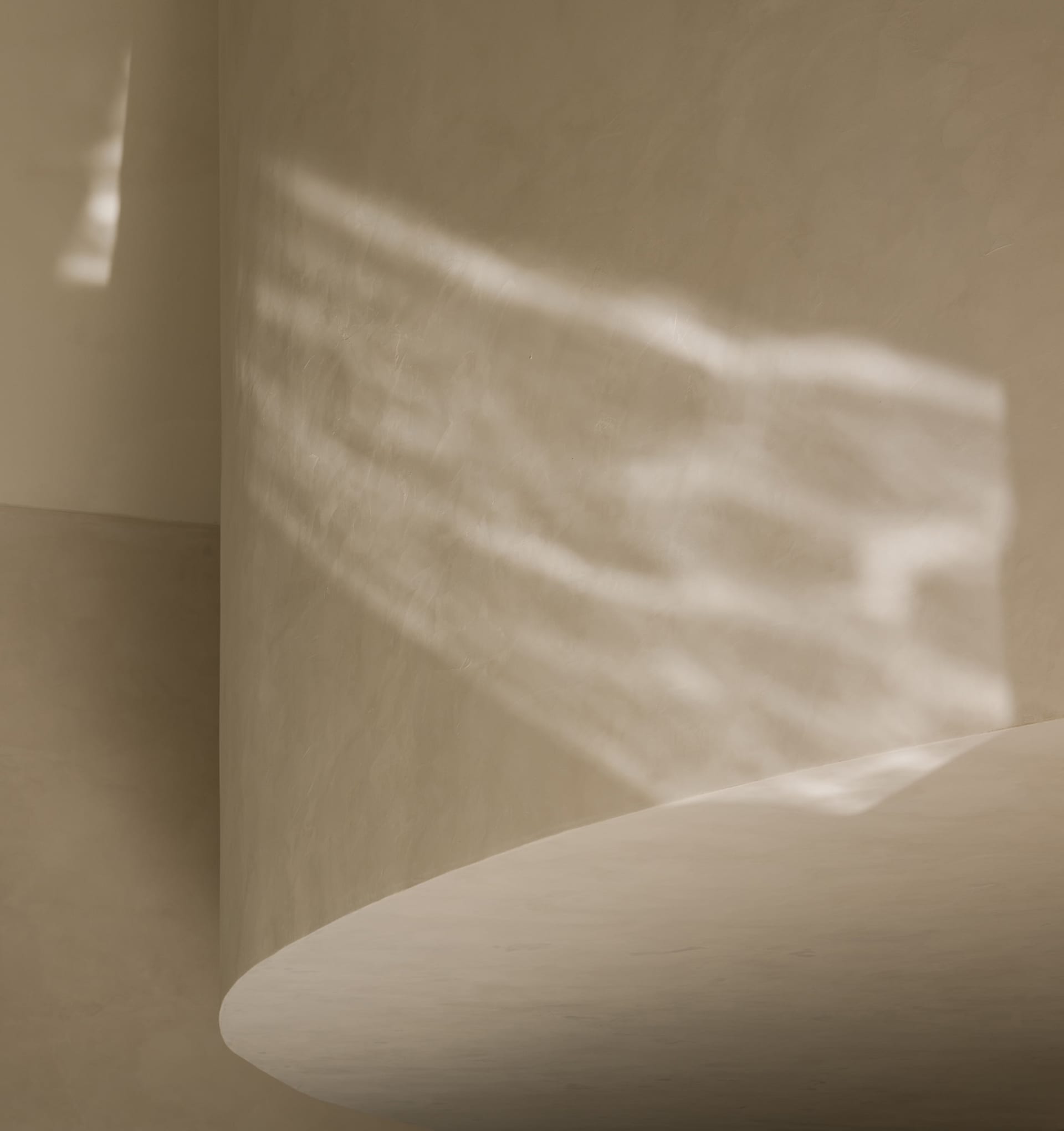 A calm interior space with a white wall, two windows, and interesting shadows created by sunlight