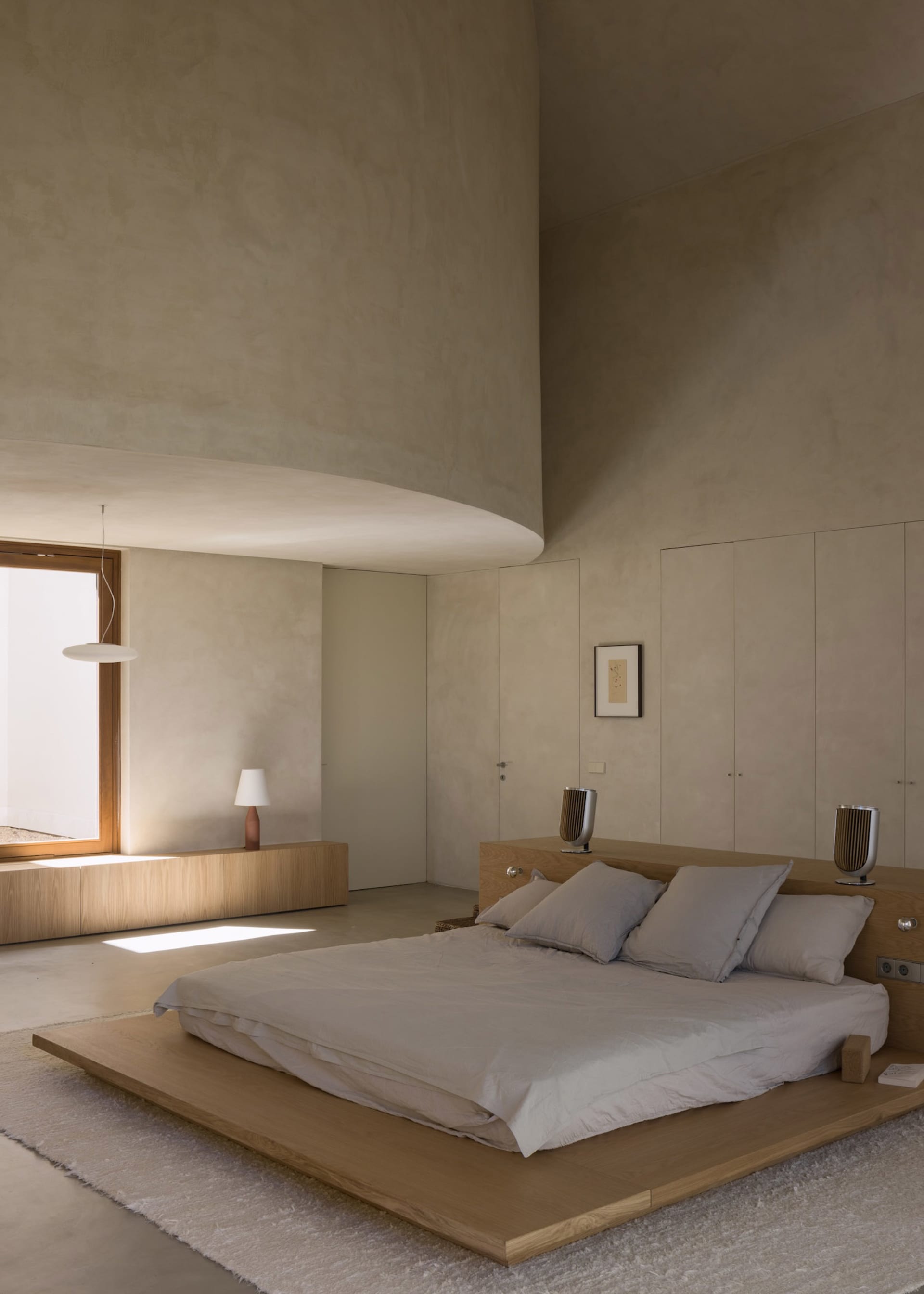 A modern bedroom with a wooden platform bed, nightstands, and lamps, creating a calm and inviting atmosphere