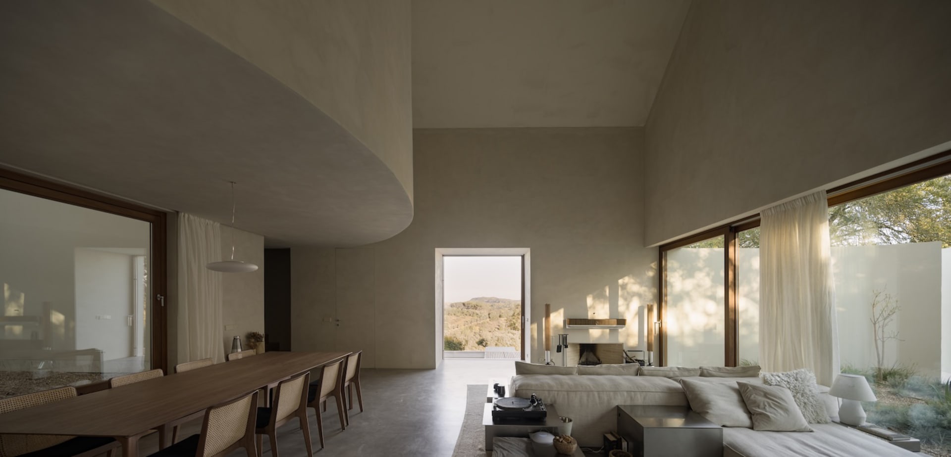 Modern open concept living space with a large couch, dining table, chairs, fireplace, and rug, featuring a contemporary and inviting atmosphere