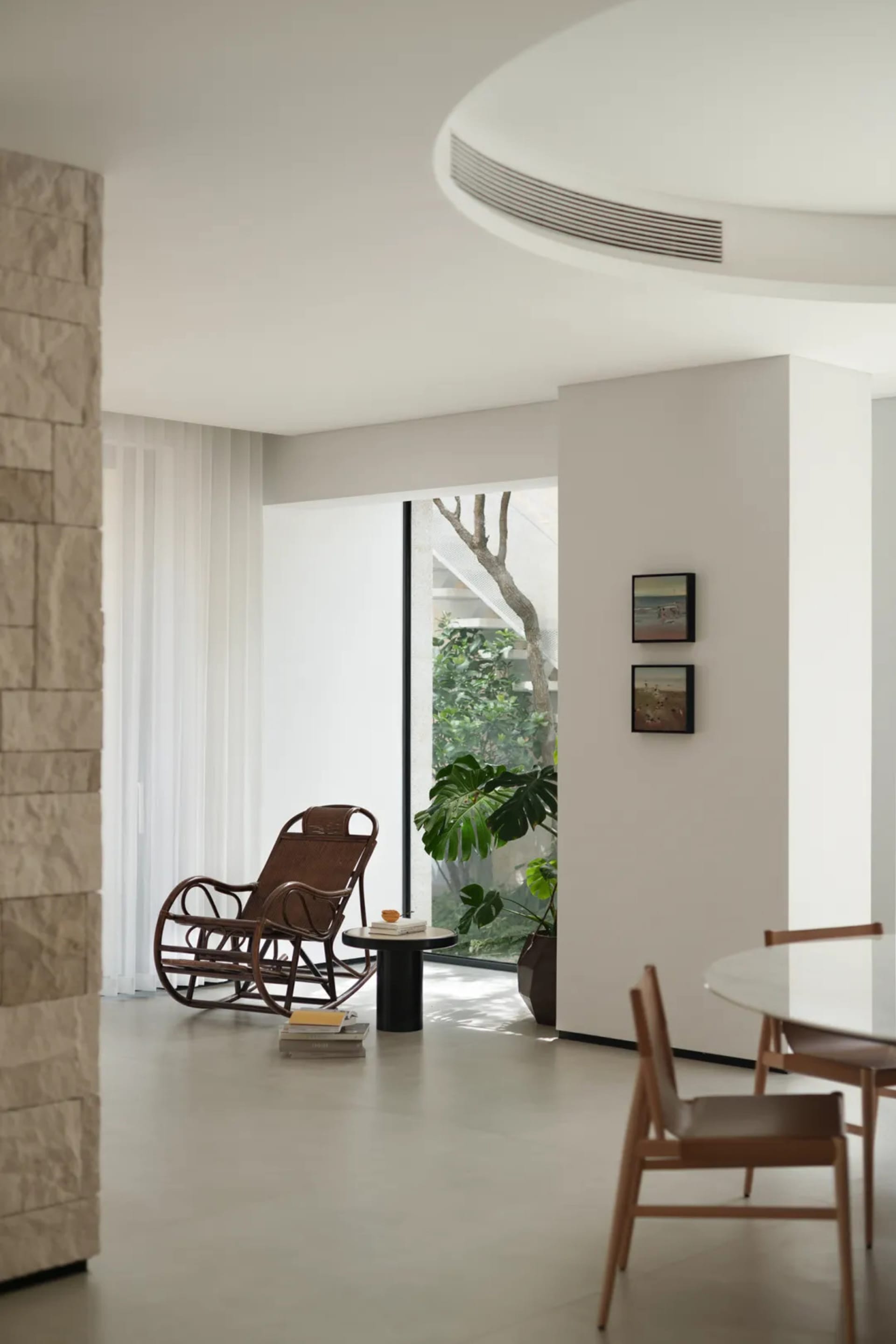 Inviting living area with white interior design, wooden and metal furniture, a dining table, potted plant, and scattered books