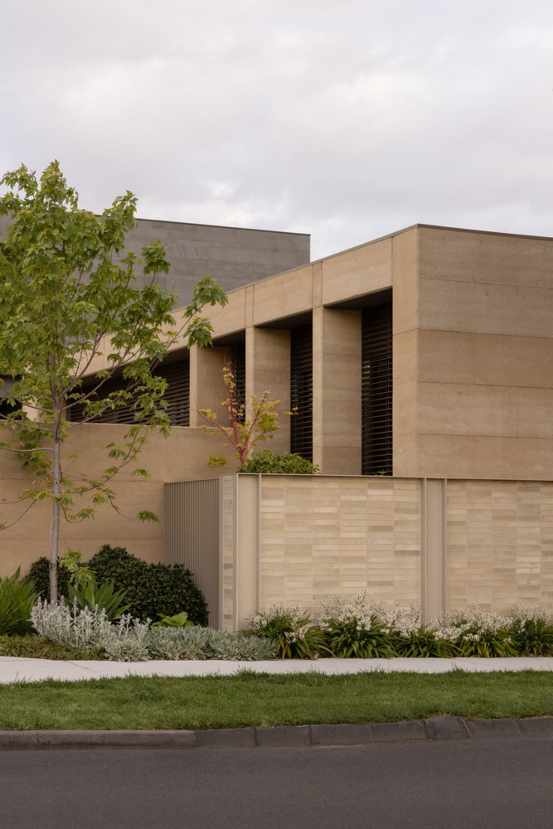 A rendered image of a brick building with a large window and trees in the foreground, set in an urban environment
