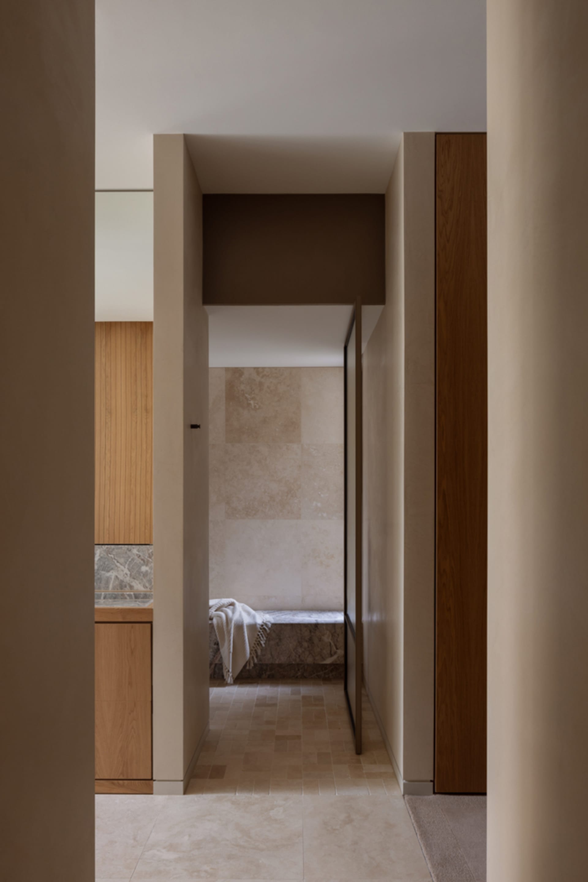 A warm and inviting hallway with wooden features, white walls, and two doorways leading to adjacent rooms