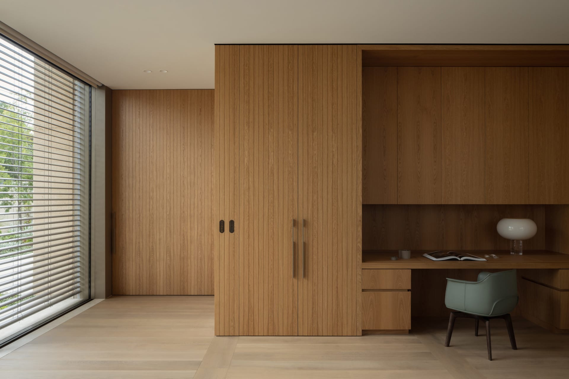 A warm and inviting bedroom with a wooden cabinet, desk, chair, and scattered books, creating a comfortable study area