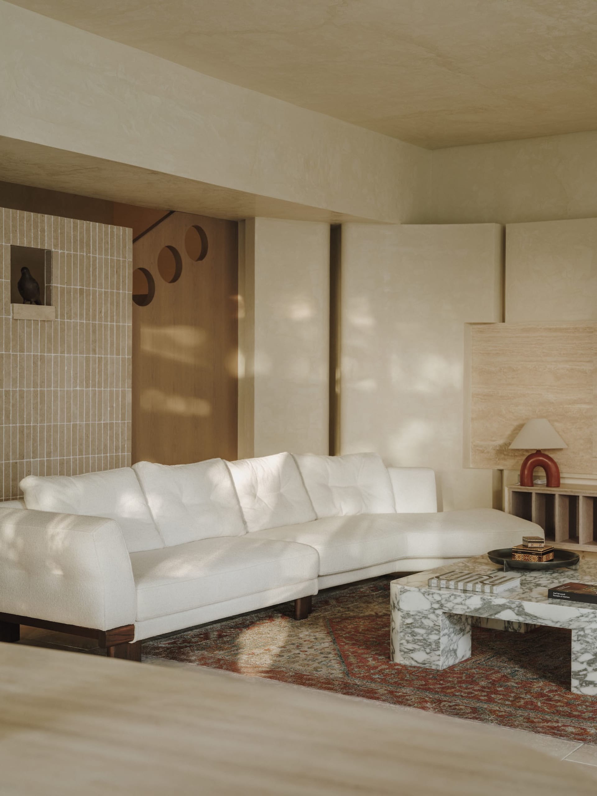 Bright and inviting living area with white couches, a coffee table, and sunlight streaming through the windows