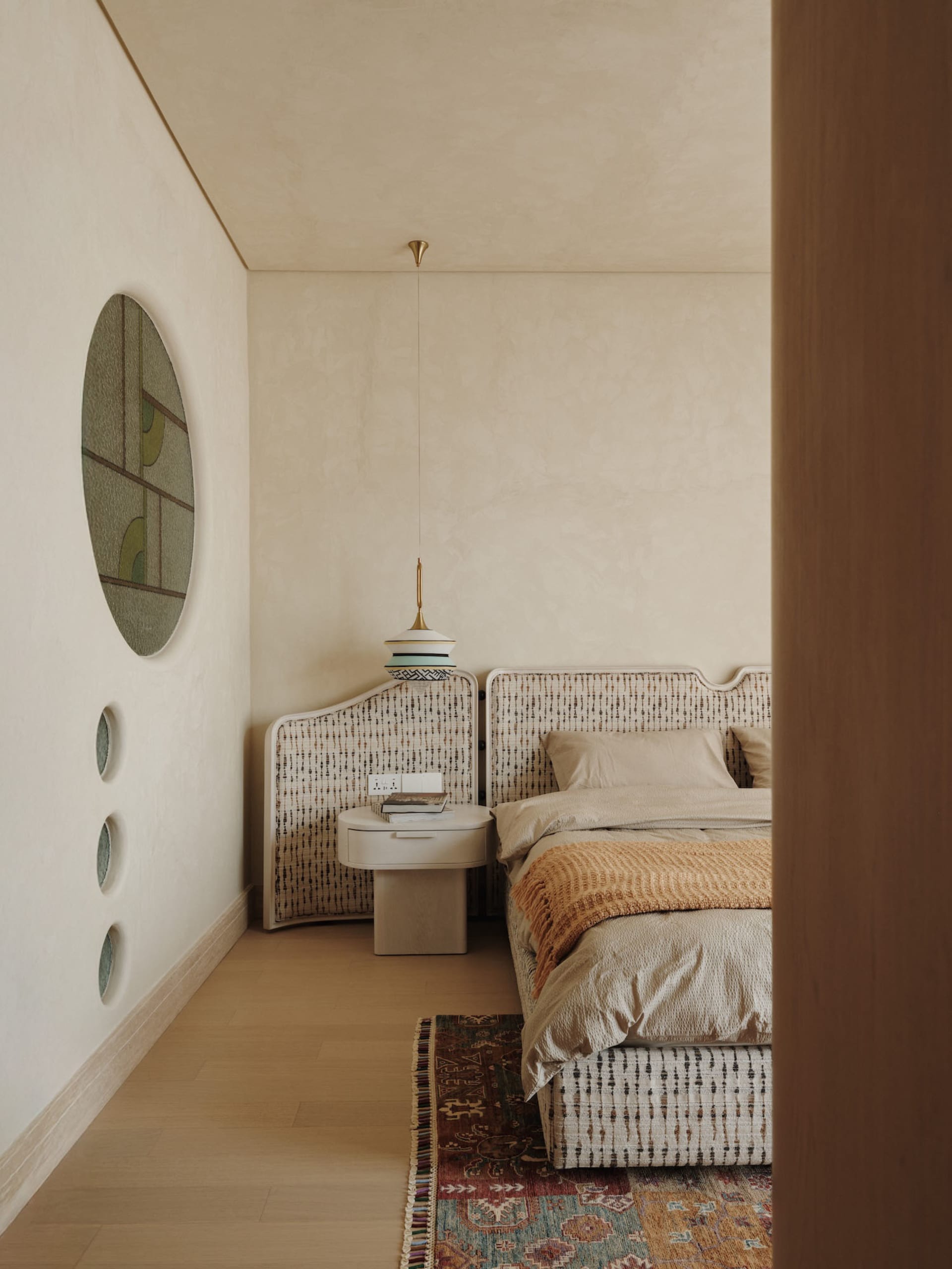 A simple bedroom with two beds and nightstands on a wooden floor, beige walls, and a minimalistic design