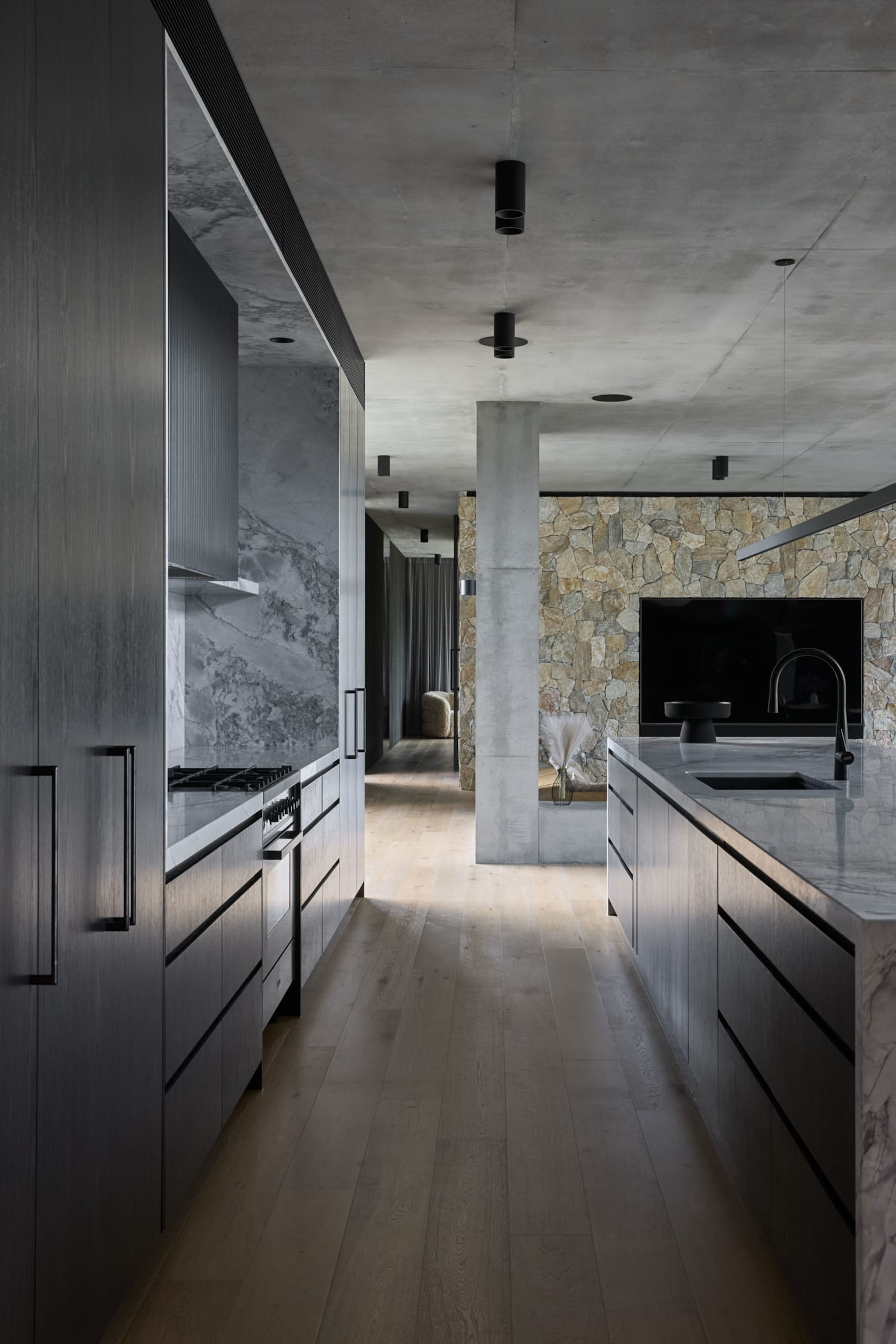Open modern living space with a kitchen island, wooden flooring, a couch, TV, and dining table
