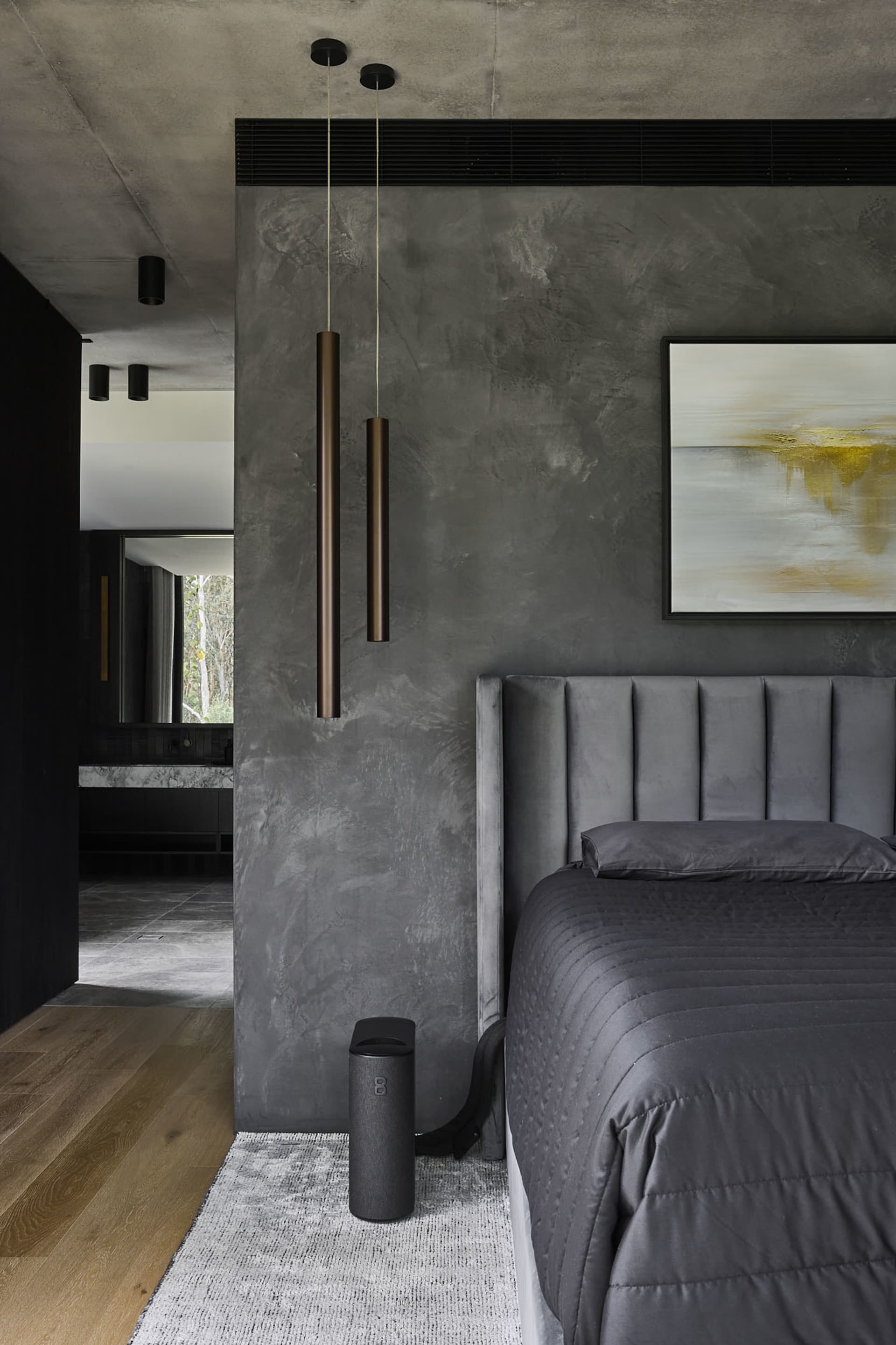 A modern bedroom with a metal bed, gray walls, and a couch, lit by lamps on either side of the bed
