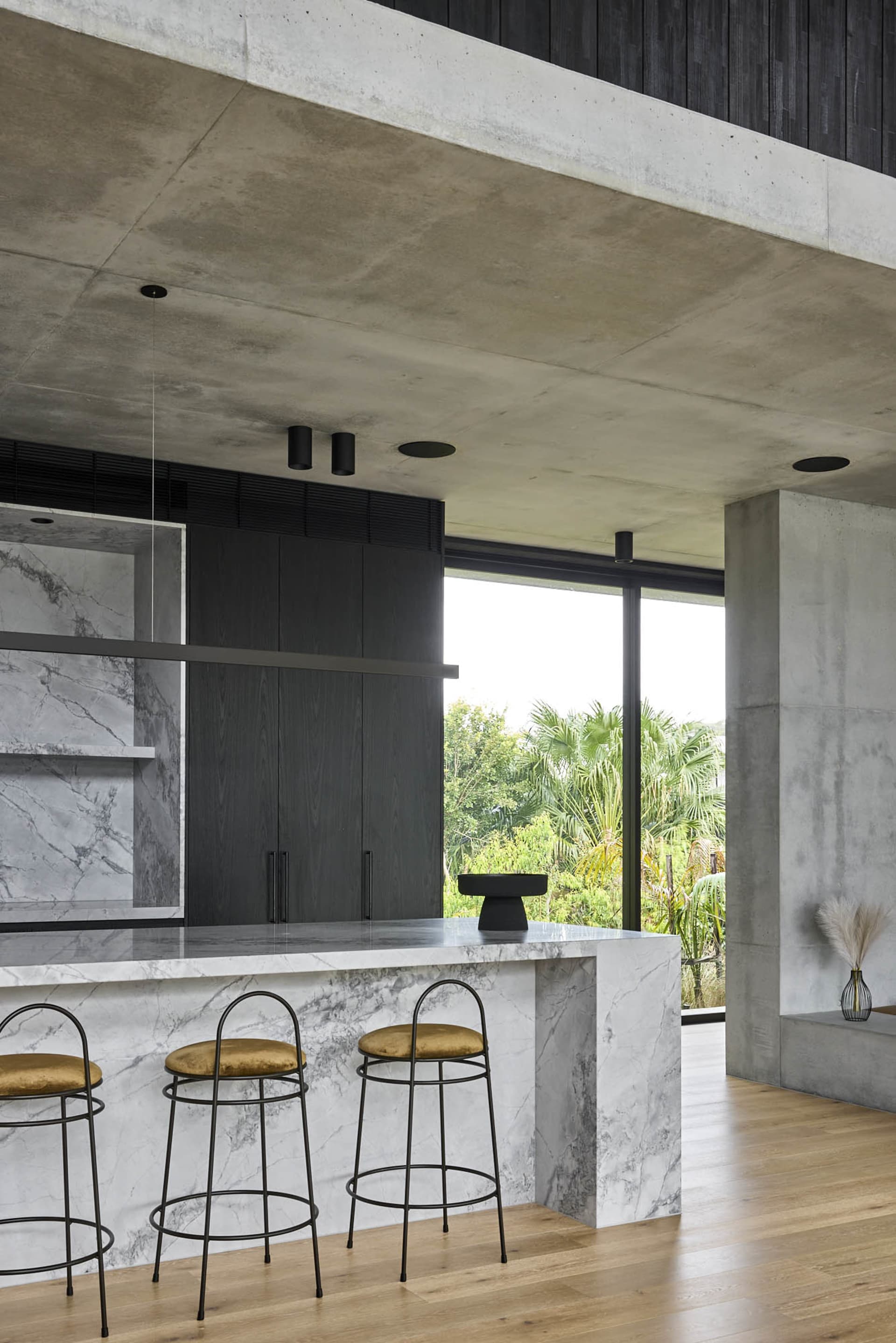 Modern kitchen with black and white theme, large island, stools, chairs, and sliding glass door to living area