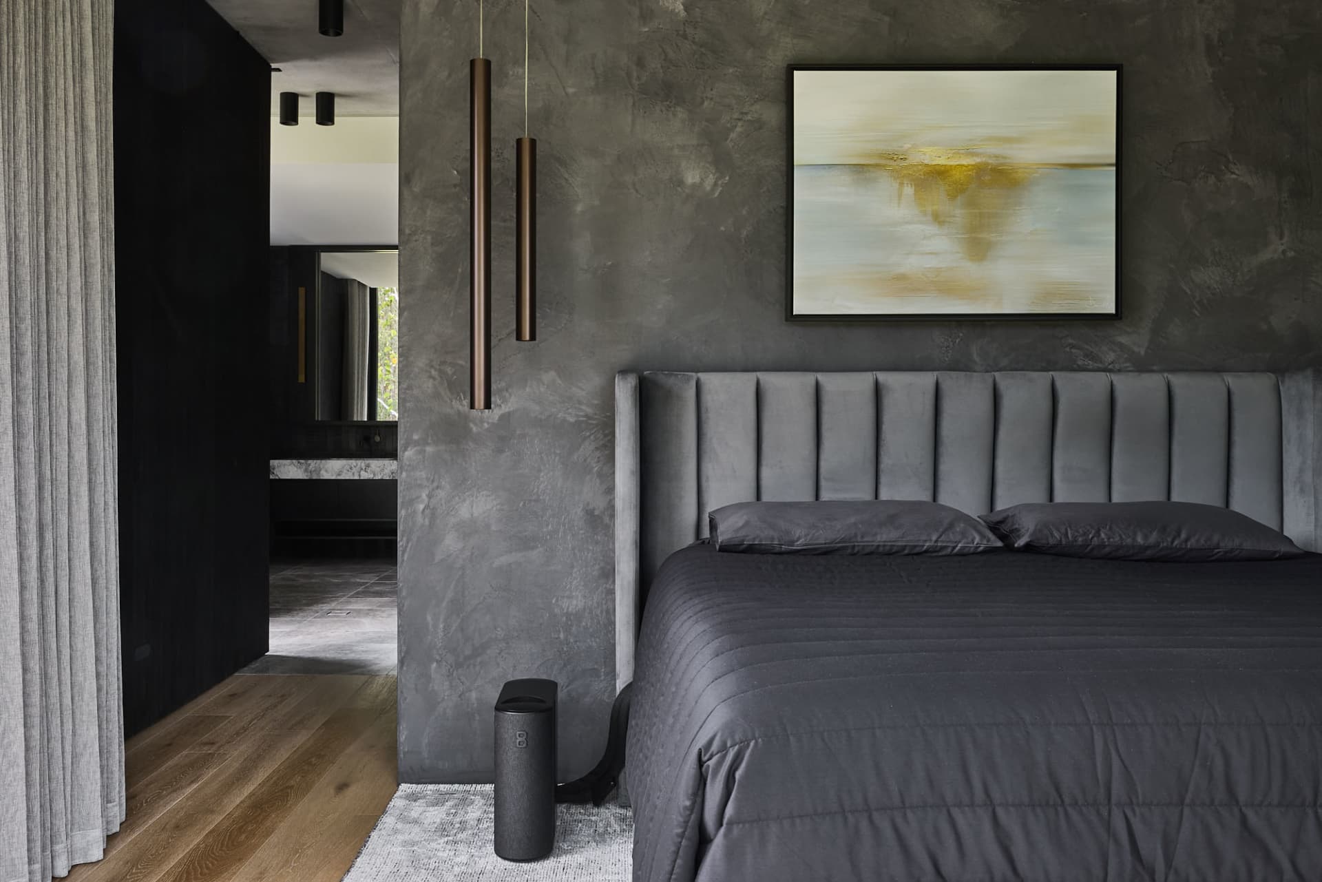 A modern bedroom with a black bed in front of a large picture, grey walls, two lamps, and a potted plant adding greenery