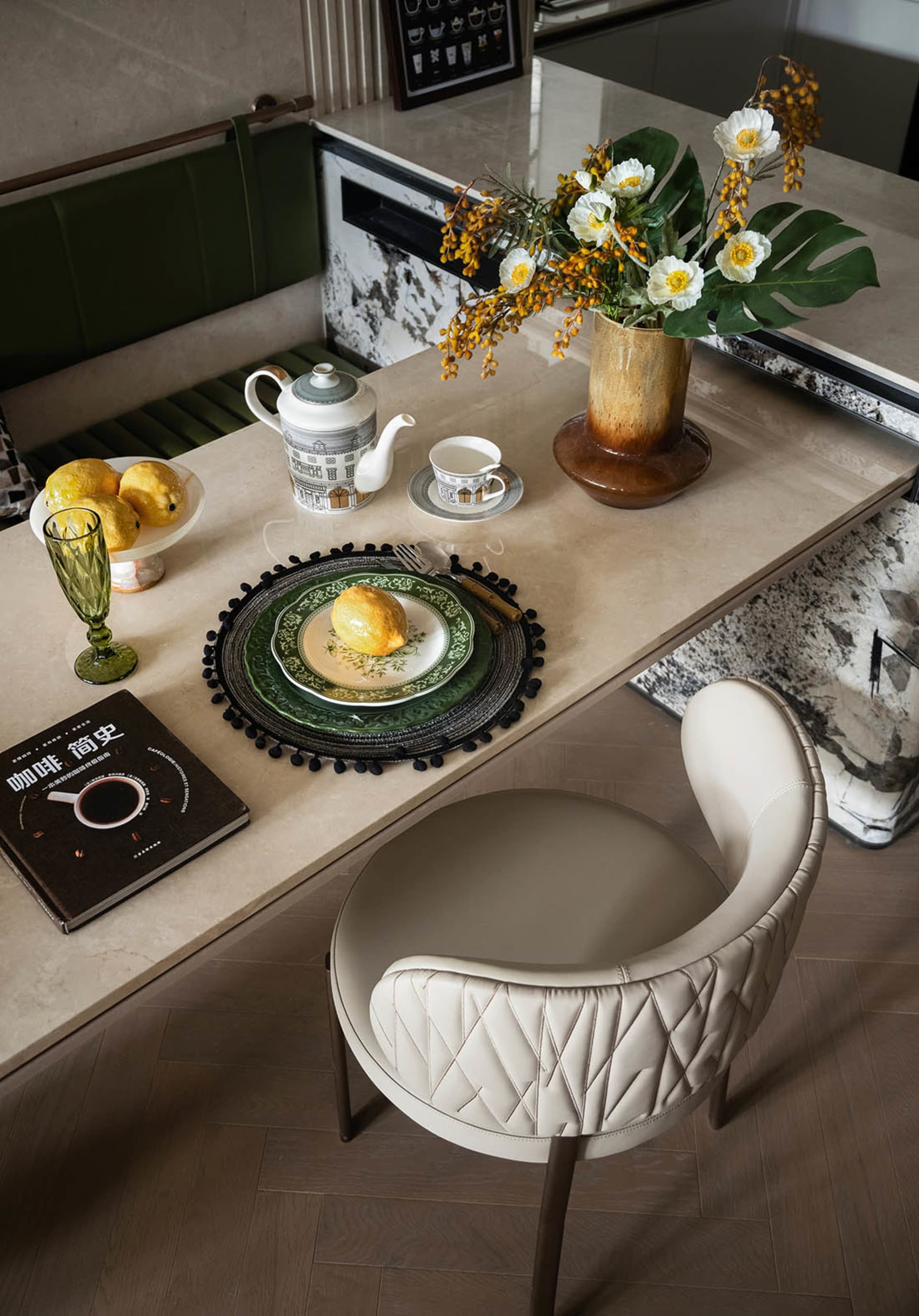 Sophisticated dining area with a white chair, table, vase of flowers, cups, and a fruit bowl