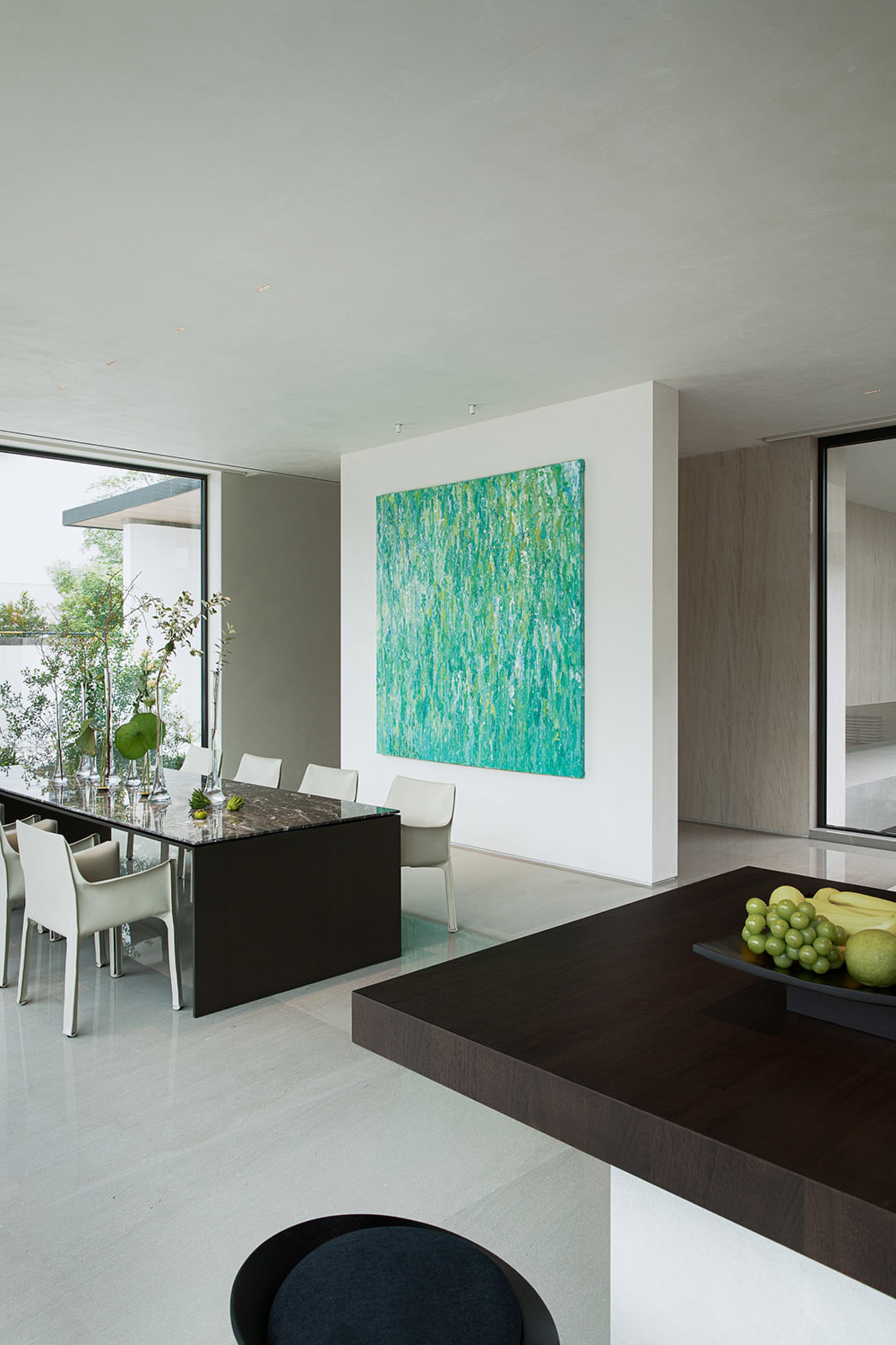 Elegant dining space with a large painting, wine glasses, and a dining table surrounded by chairs