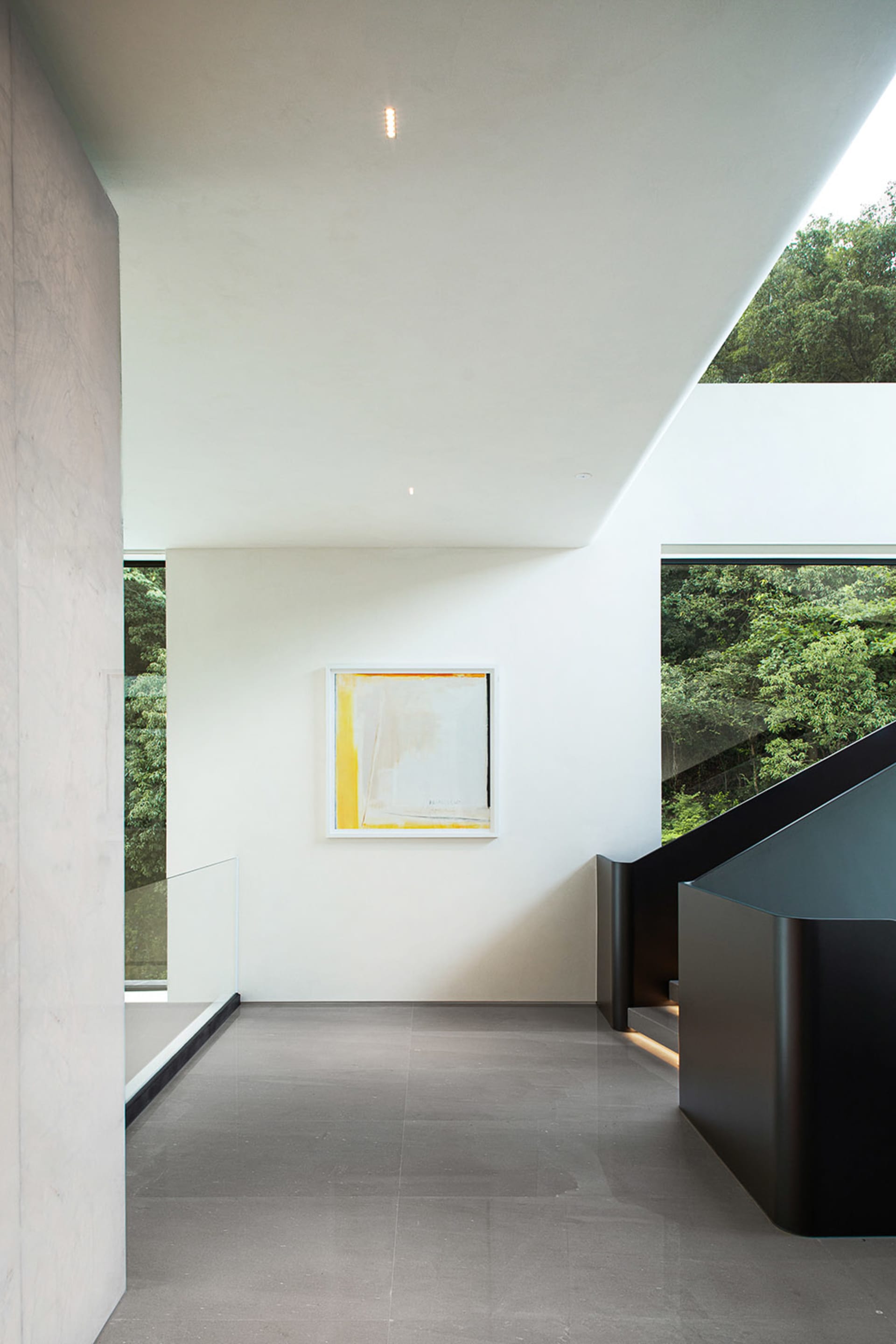 Bright open living area with a large window, two staircases, and a painting on the wall