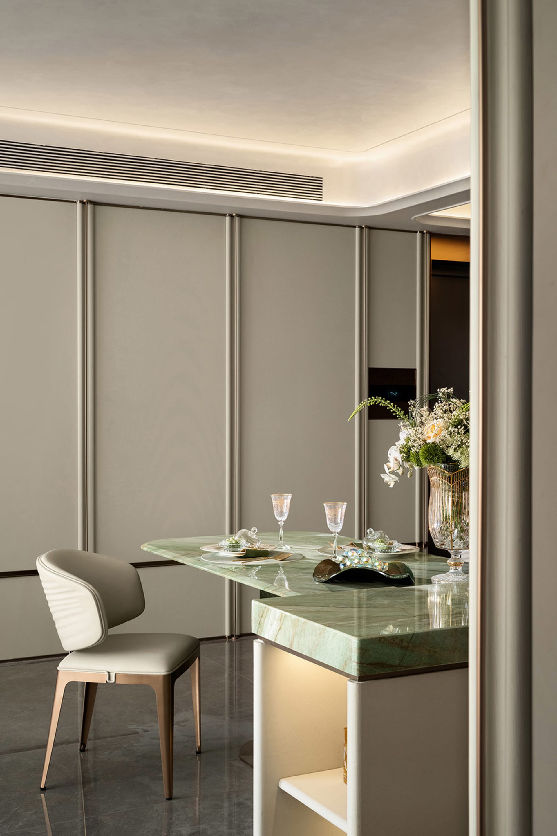 Elegant dining room with gray walls, a dining table, chairs, wine glasses, and a vase with flowers