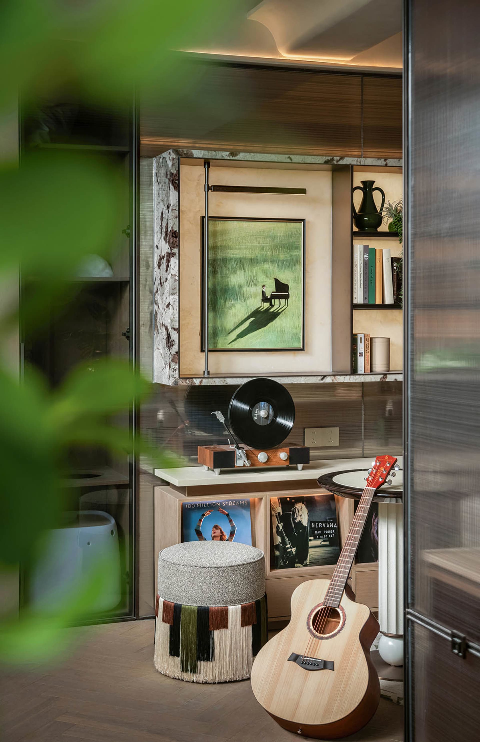 Cozy living area with a guitar, books, and a vase, featuring warm and inviting decor