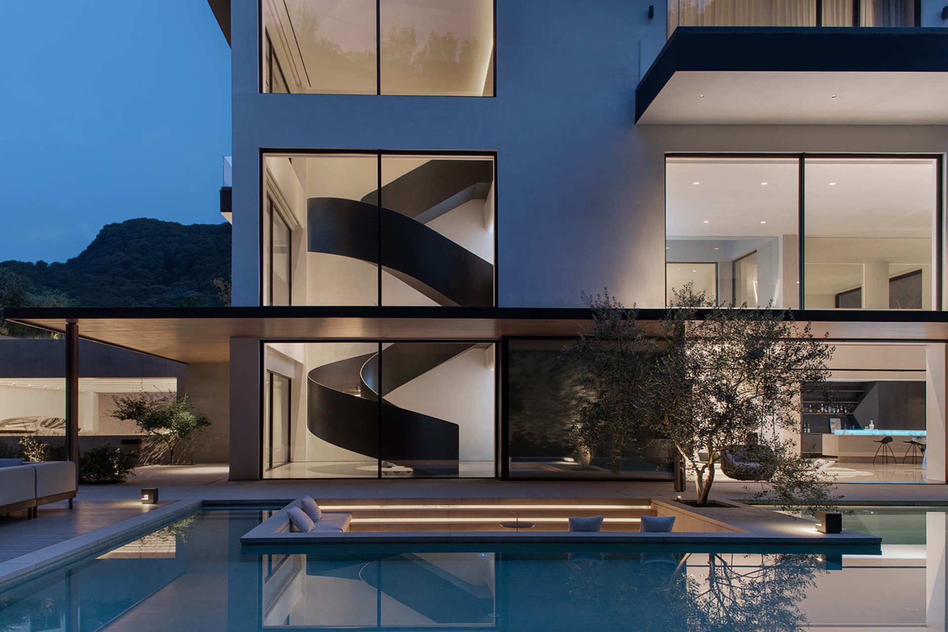 A modern house with a swimming pool and surrounding seating area, featuring large windows and a comfortable atmosphere